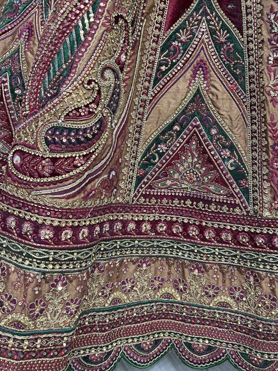Richly embroidered Indian ethnic wear with paisley and floral motifs in maroon, green, and gold