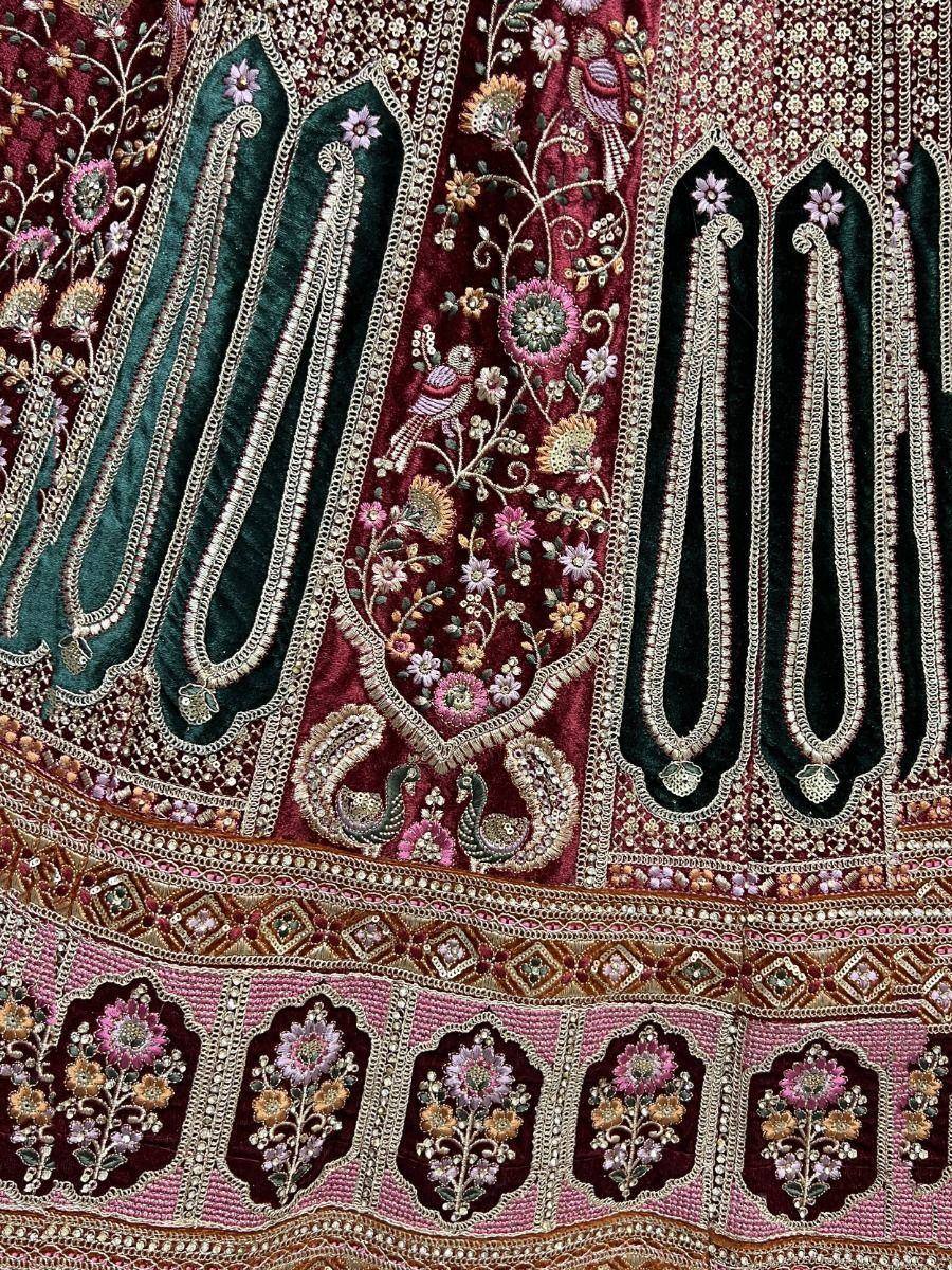 Richly embroidered Indian lehenga with floral and paisley motifs in maroon, green, and pink velvet
