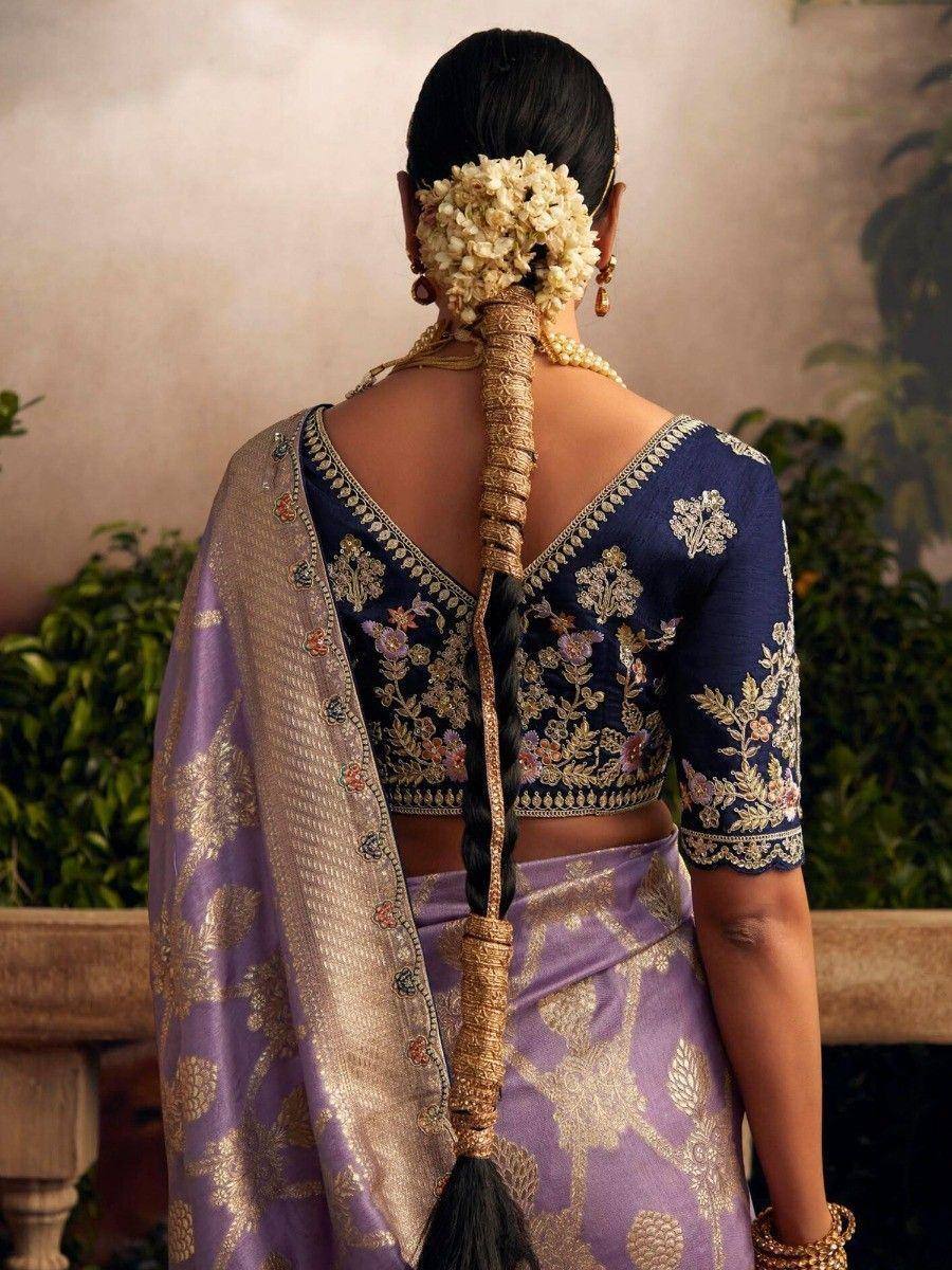 Elegant navy blue embroidered blouse with purple saree, floral hair accessory, and gold jewelry for Indian ethnic wear
