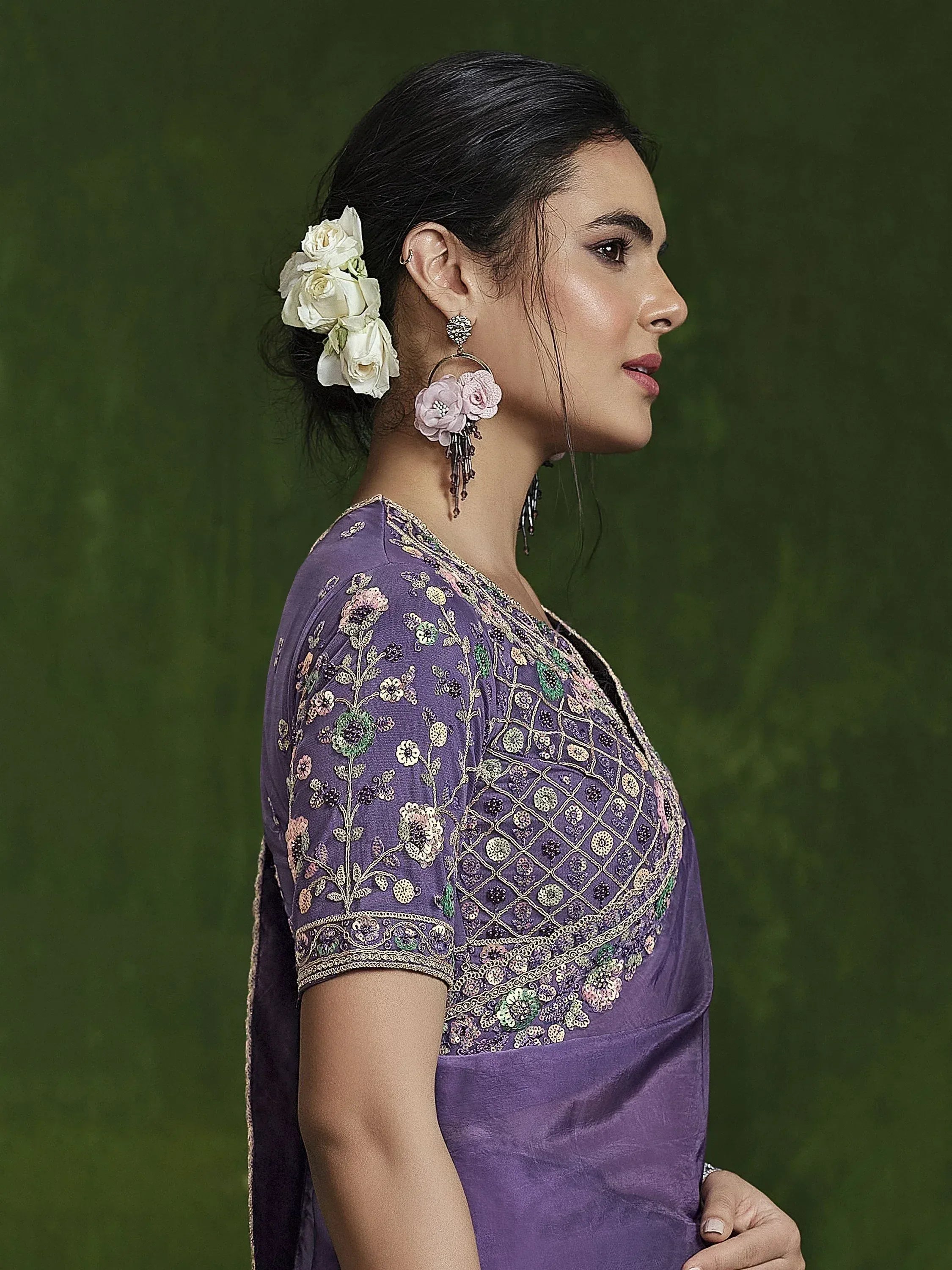 Purple embroidered ethnic gown with floral detailing, styled with white roses and floral earrings