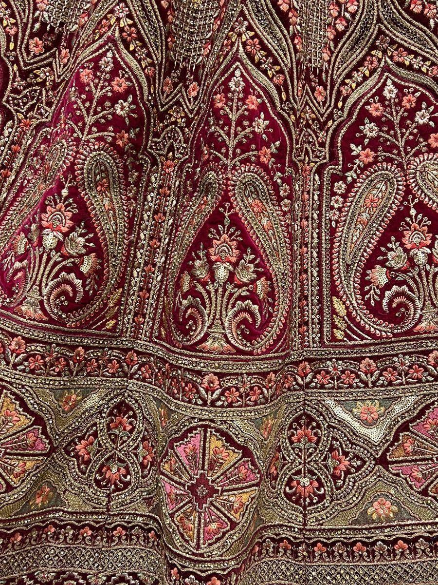 Rich maroon ethnic fabric with intricate gold and pink floral embroidery, perfect for designer lehenga or saree.
