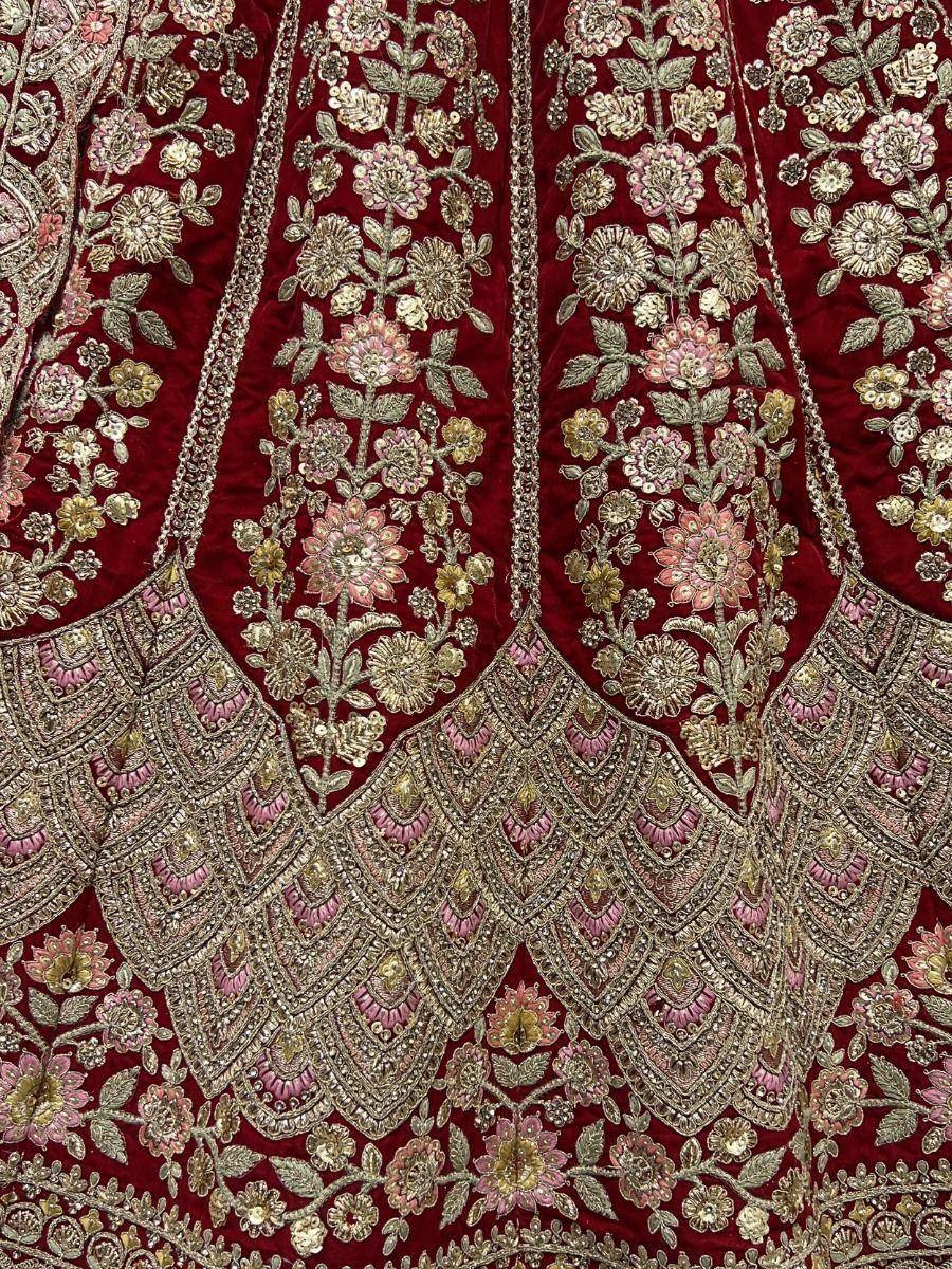 Rich maroon velvet lehenga with intricate gold and pink floral embroidery, perfect for Indian ethnic wear.