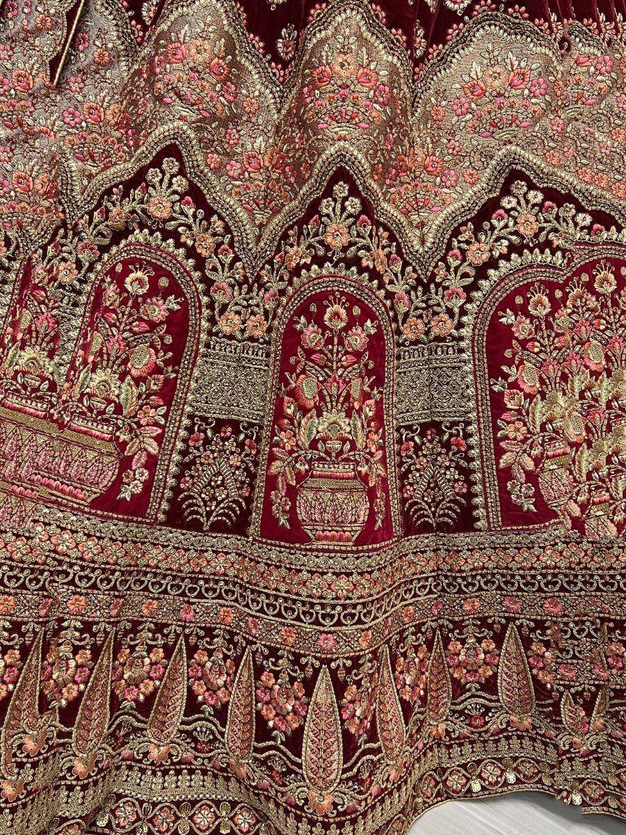 Rich maroon velvet lehenga with intricate gold floral embroidery and vase motifs, perfect for Indian weddings.