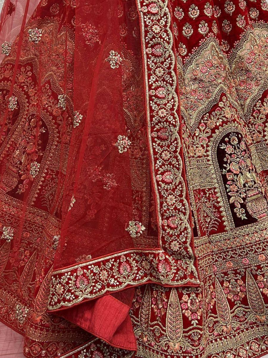 Red velvet lehenga choli with intricate gold and pink floral embroidery, perfect for Indian weddings