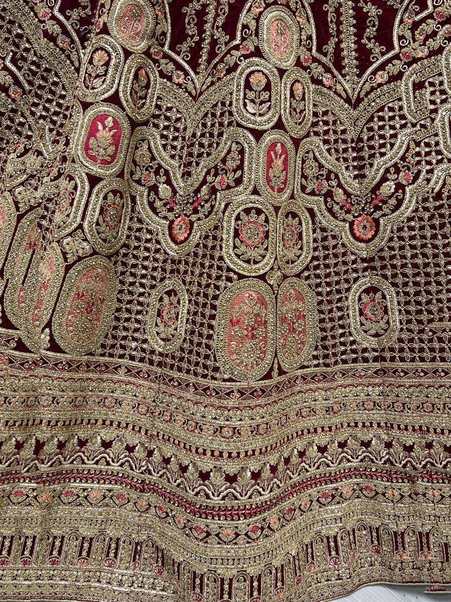 Luxury maroon velvet lehenga with intricate gold and pink embroidery, perfect for Indian ethnic wear.