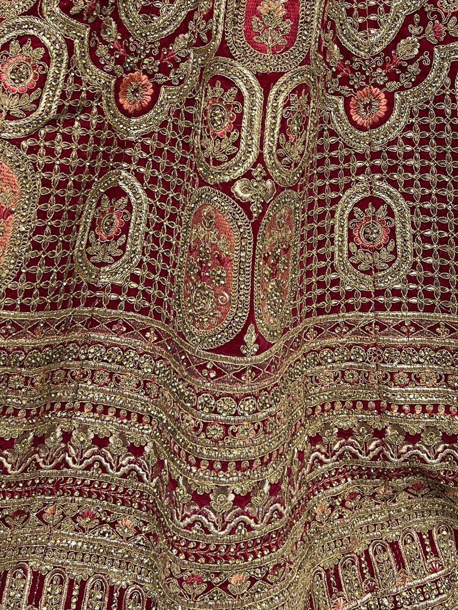 Rich maroon ethnic fabric with gold embroidery and floral motifs, perfect for designer lehenga or saree
