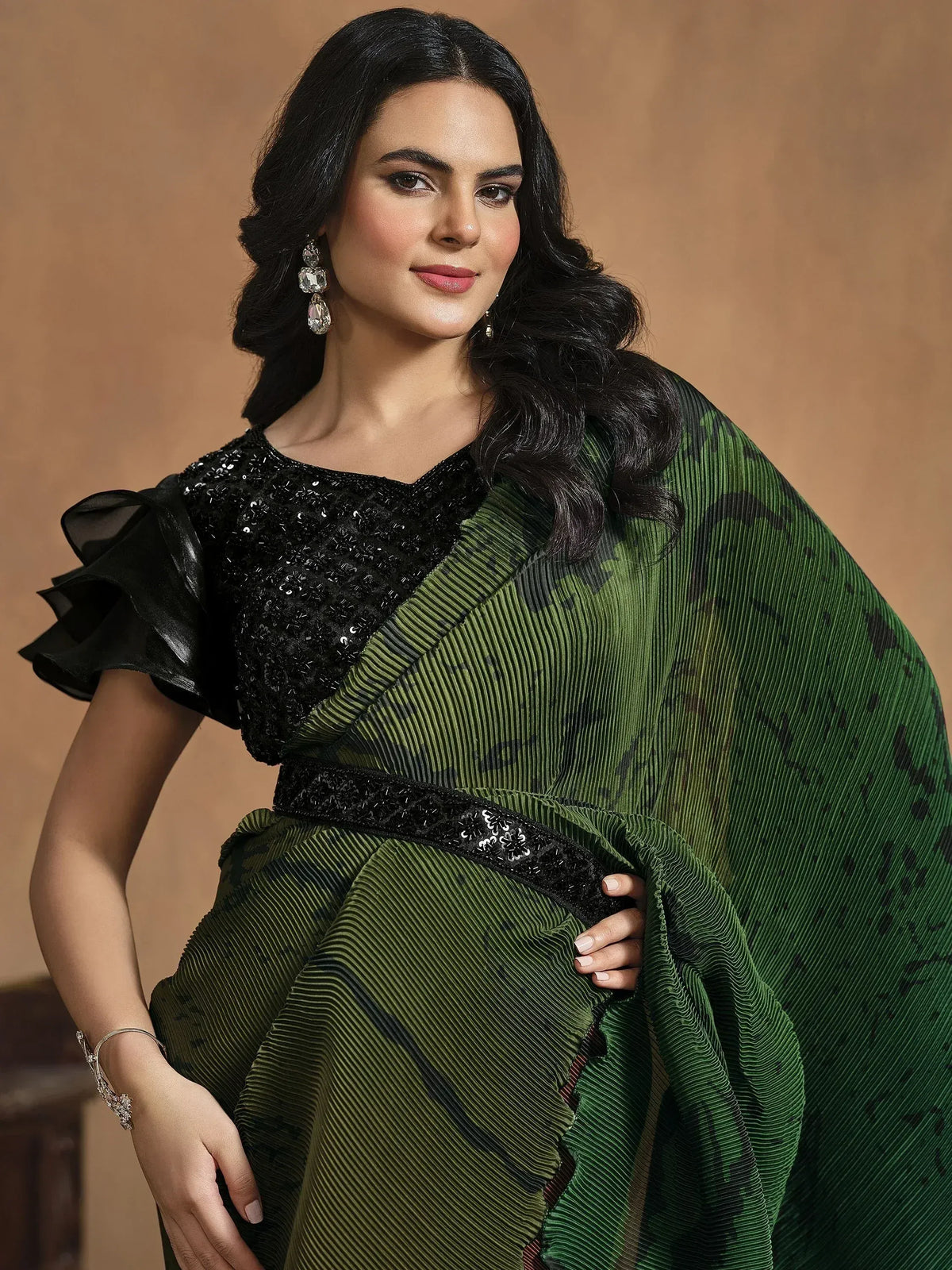 Elegant green pleated saree with black sequin blouse, perfect for Indian ethnic wear occasions.