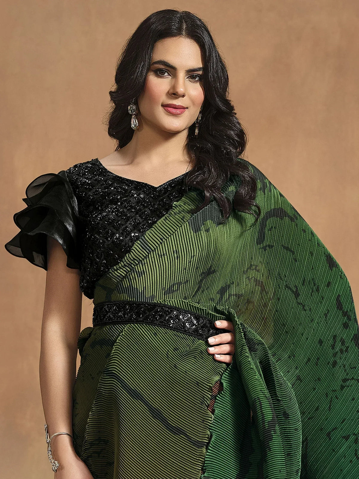 Elegant green pleated saree with black embellished blouse, perfect for ethnic occasions.