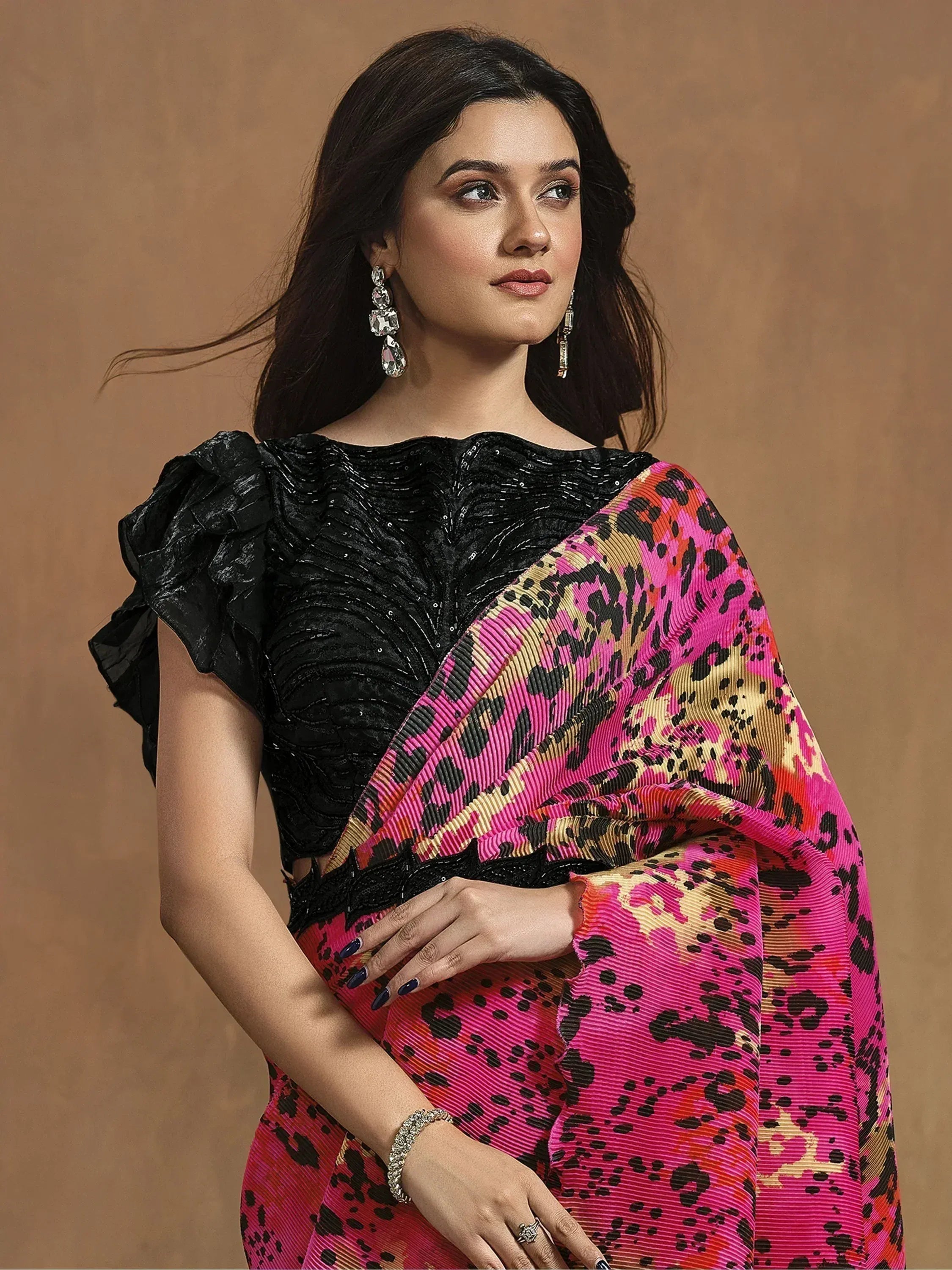 Woman in vibrant pink leopard print saree with black sequined blouse, ethnic wear