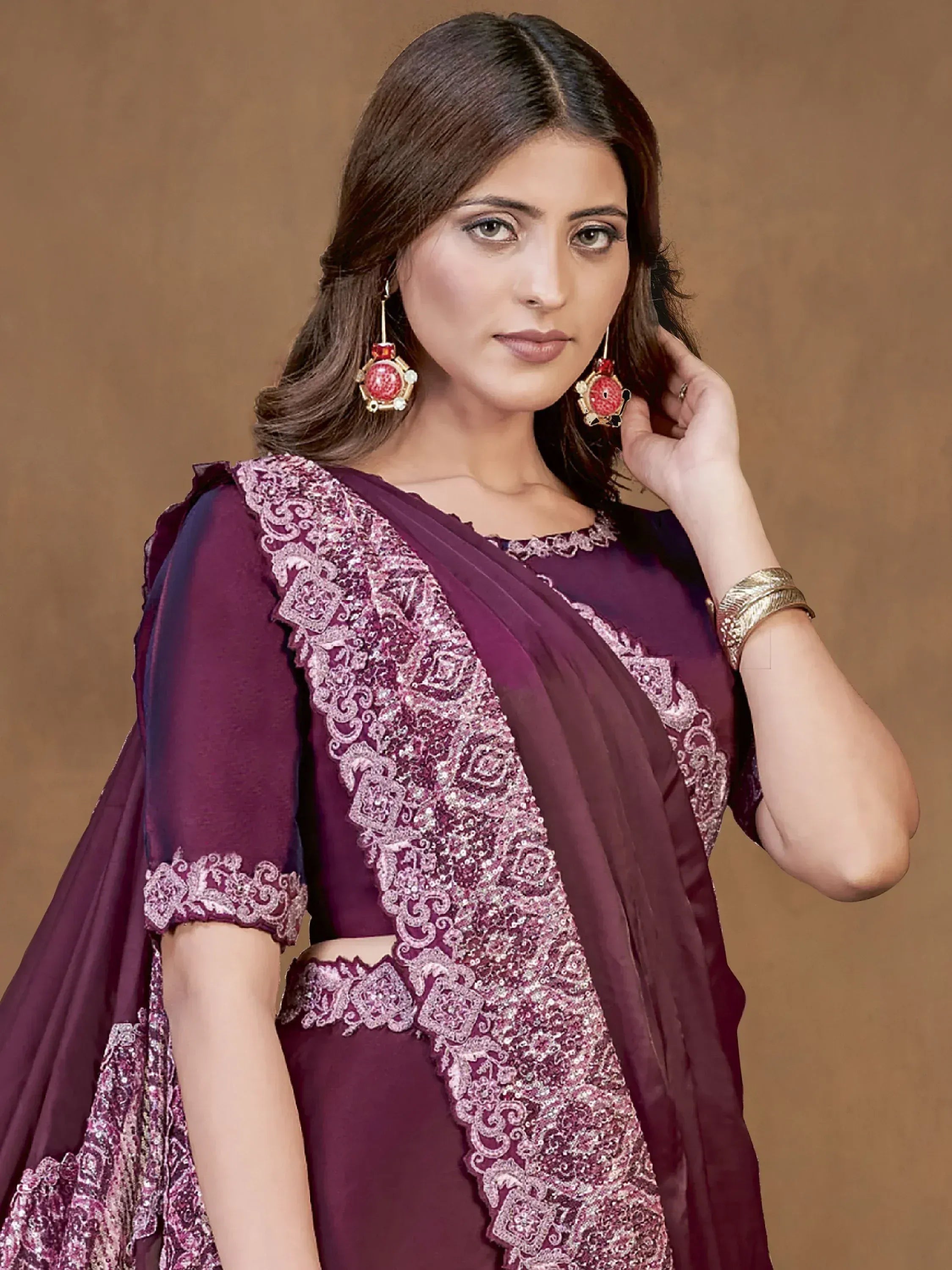 Elegant maroon ethnic saree with intricate embroidery and sequin work, paired with statement earrings.
