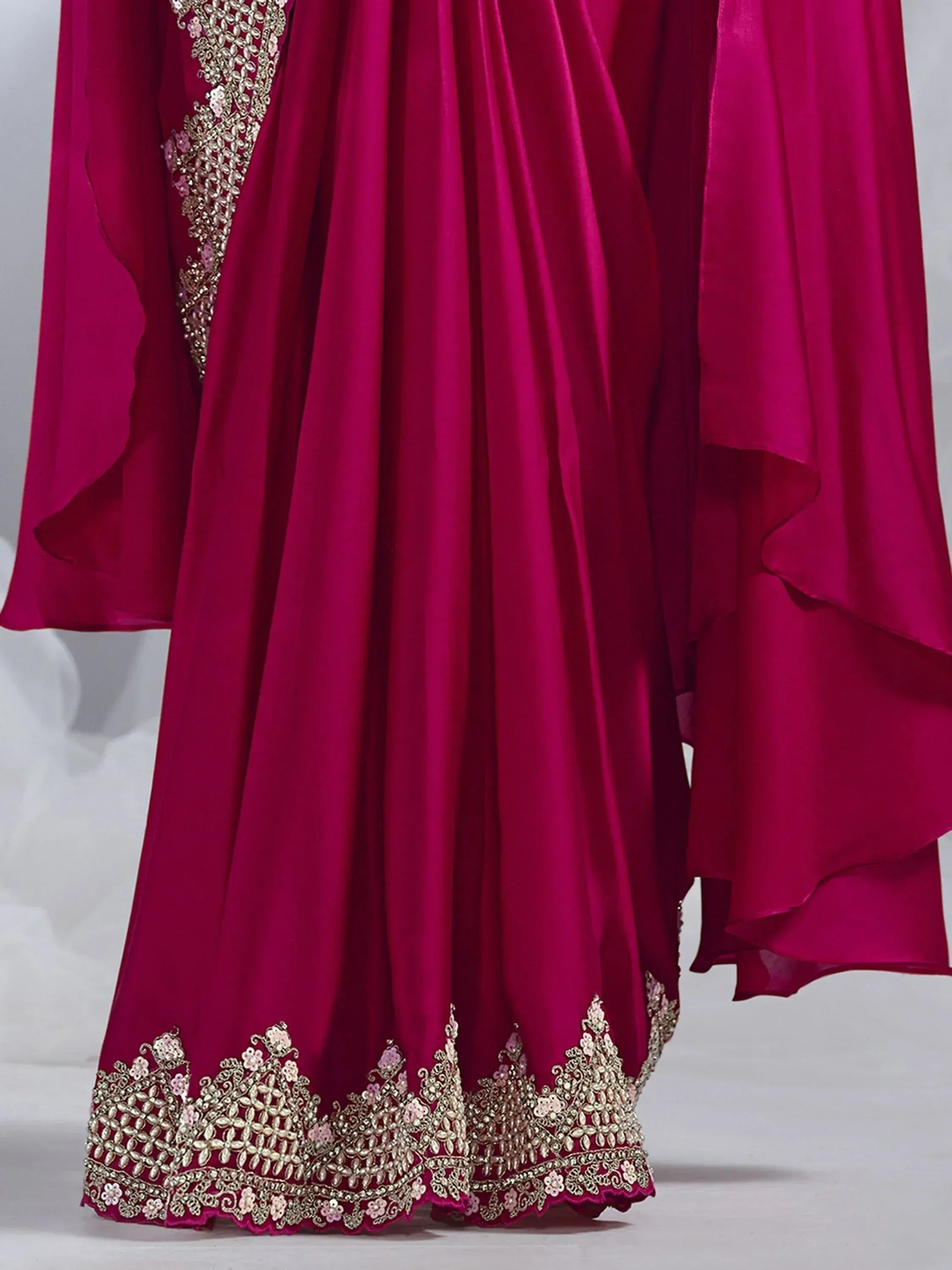 Fuchsia ethnic gown with gold floral embroidery and ruffled hem, perfect for Indian weddings or parties.