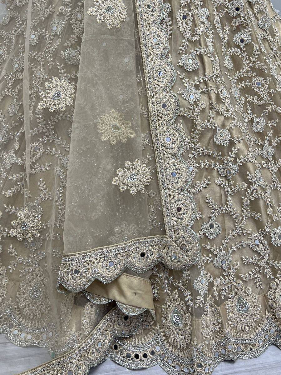 Beige designer lehenga choli with intricate gold embroidery and mirror work, perfect for Indian ethnic wear.