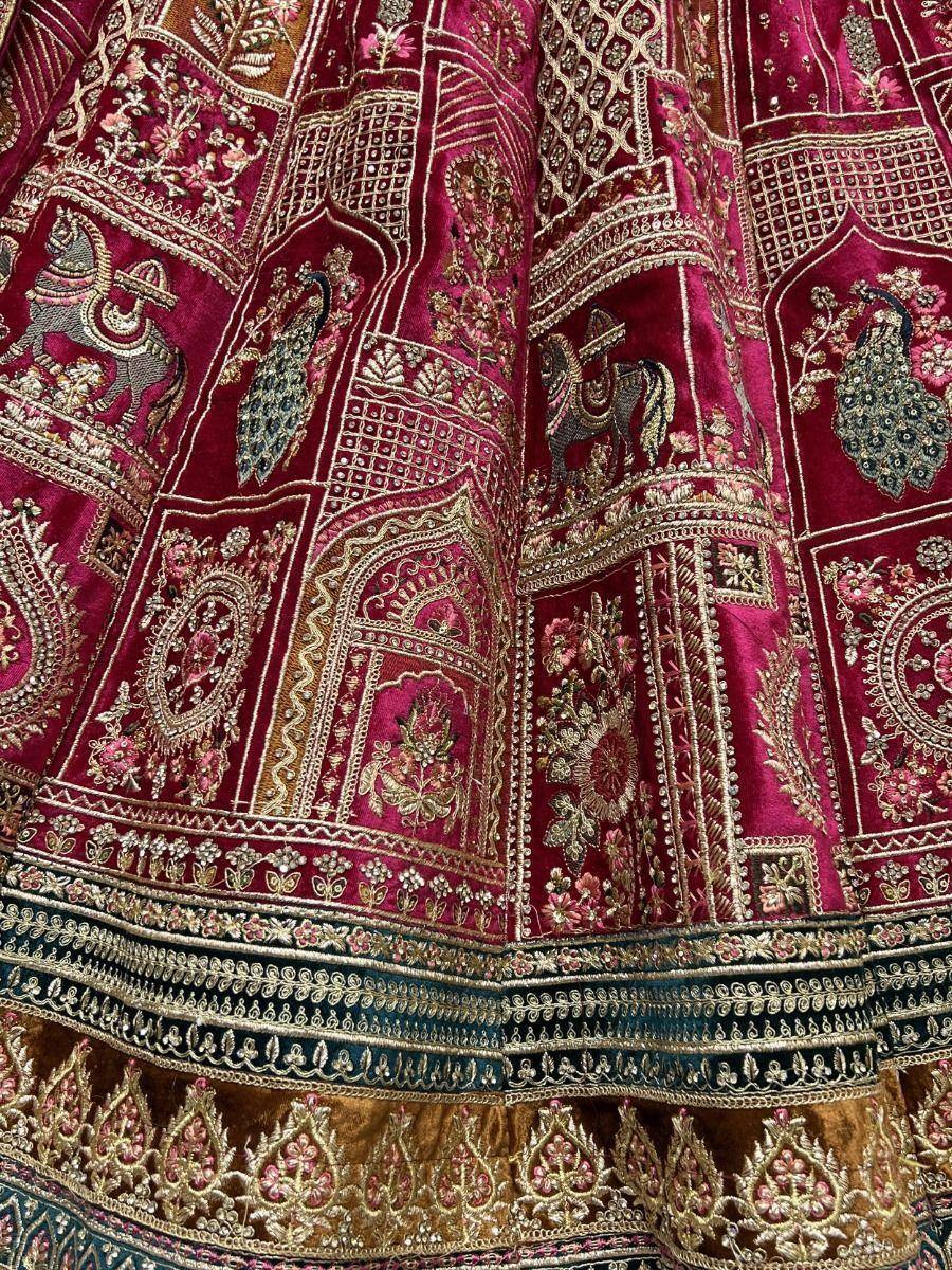 Richly embroidered maroon lehenga with peacock and horse motifs, gold threadwork, and detailed border designs.