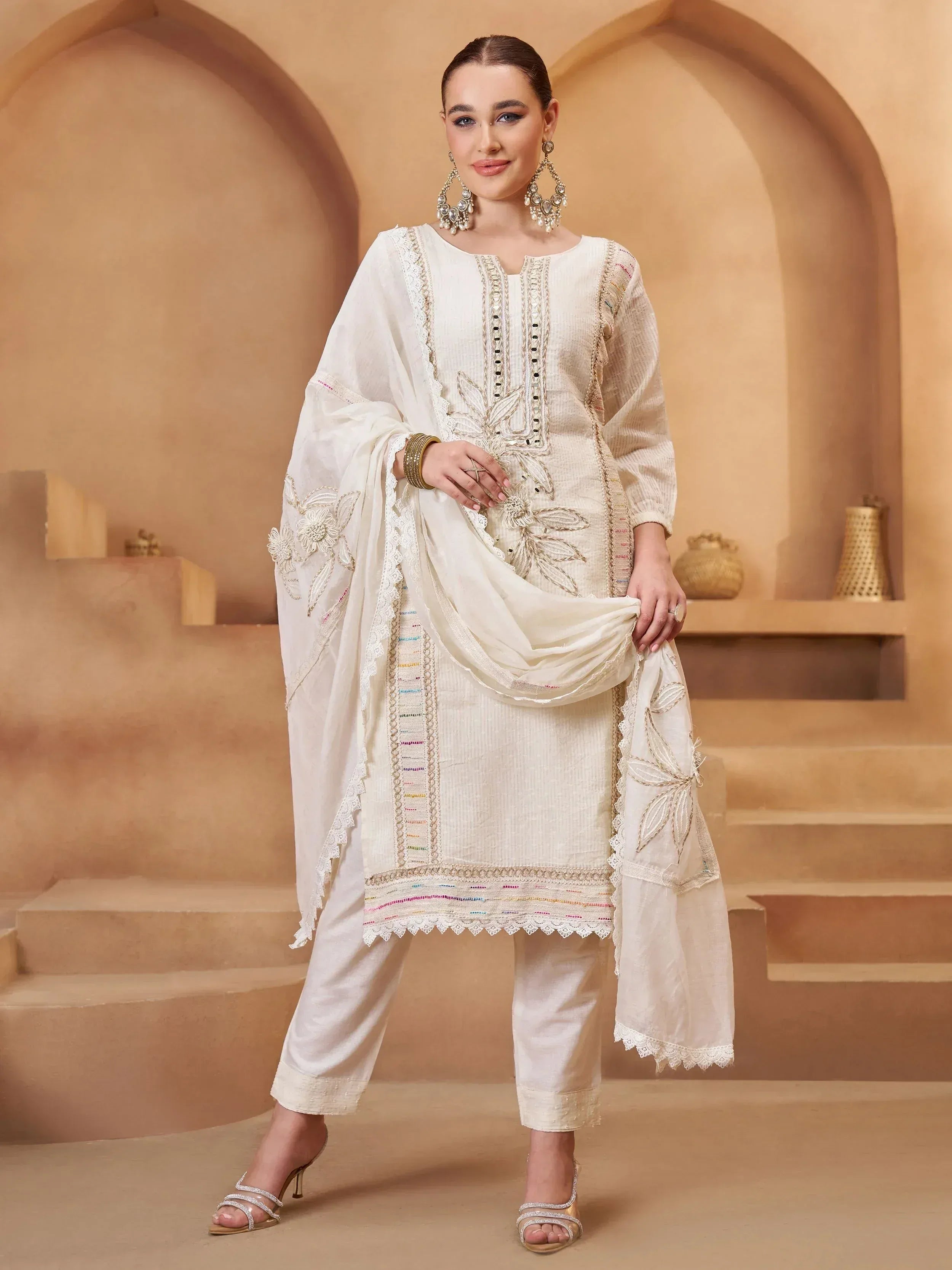 Elegant white embroidered salwar kameez with floral detailing and lace trim, perfect for festive occasions.