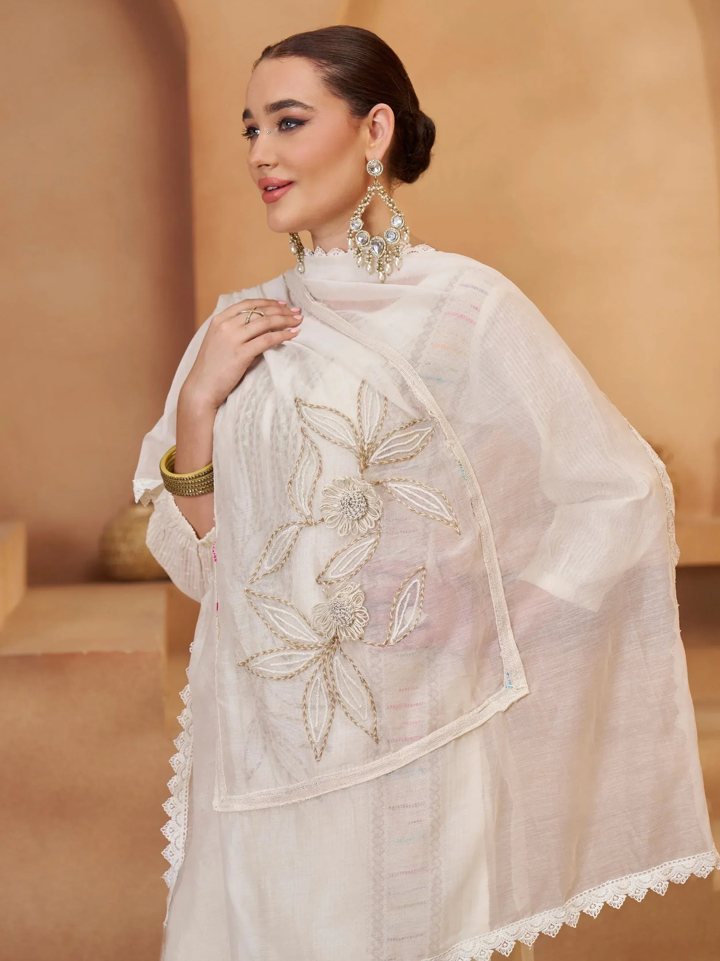 Elegant white ethnic outfit with floral embroidery and lace detailing, paired with statement jewelry.