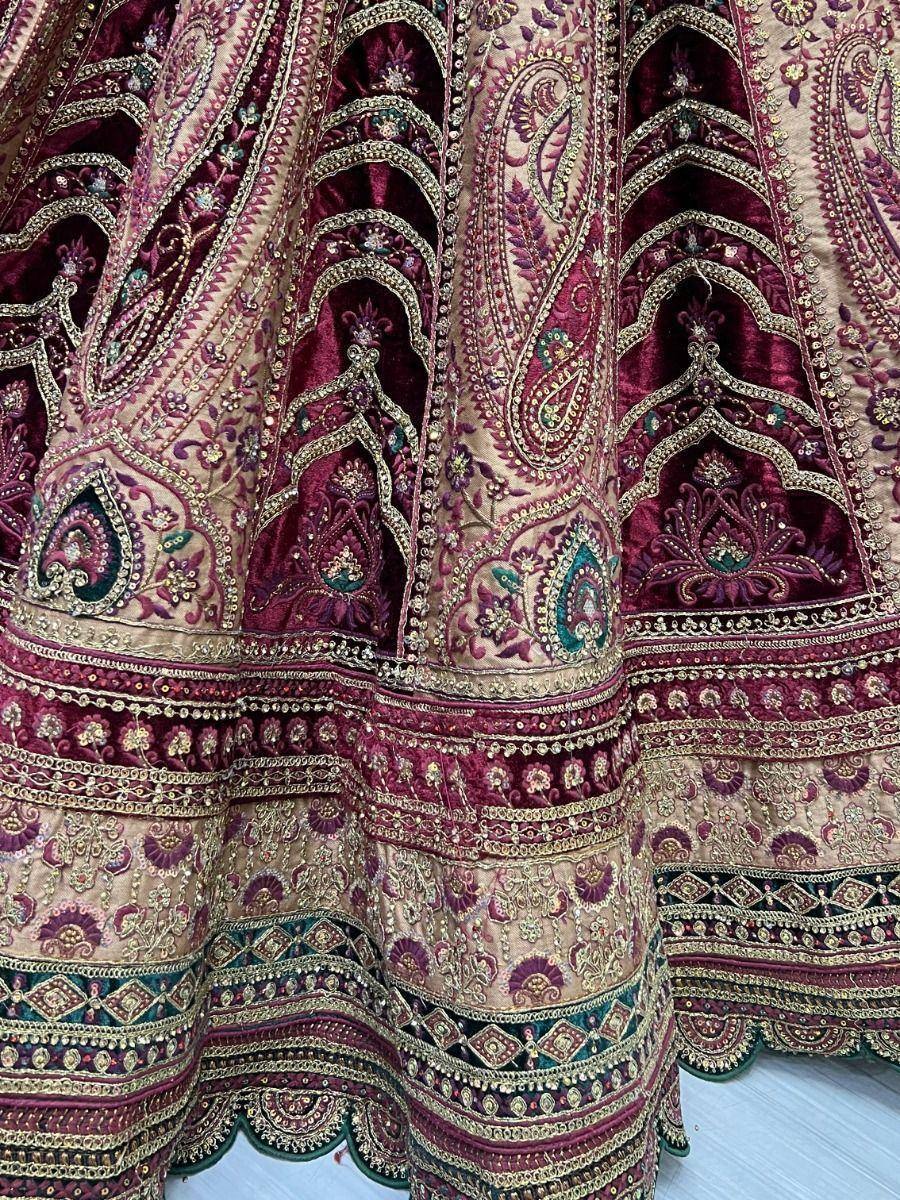 Luxury maroon and gold embroidered lehenga with intricate paisley and floral motifs, perfect for Indian weddings.