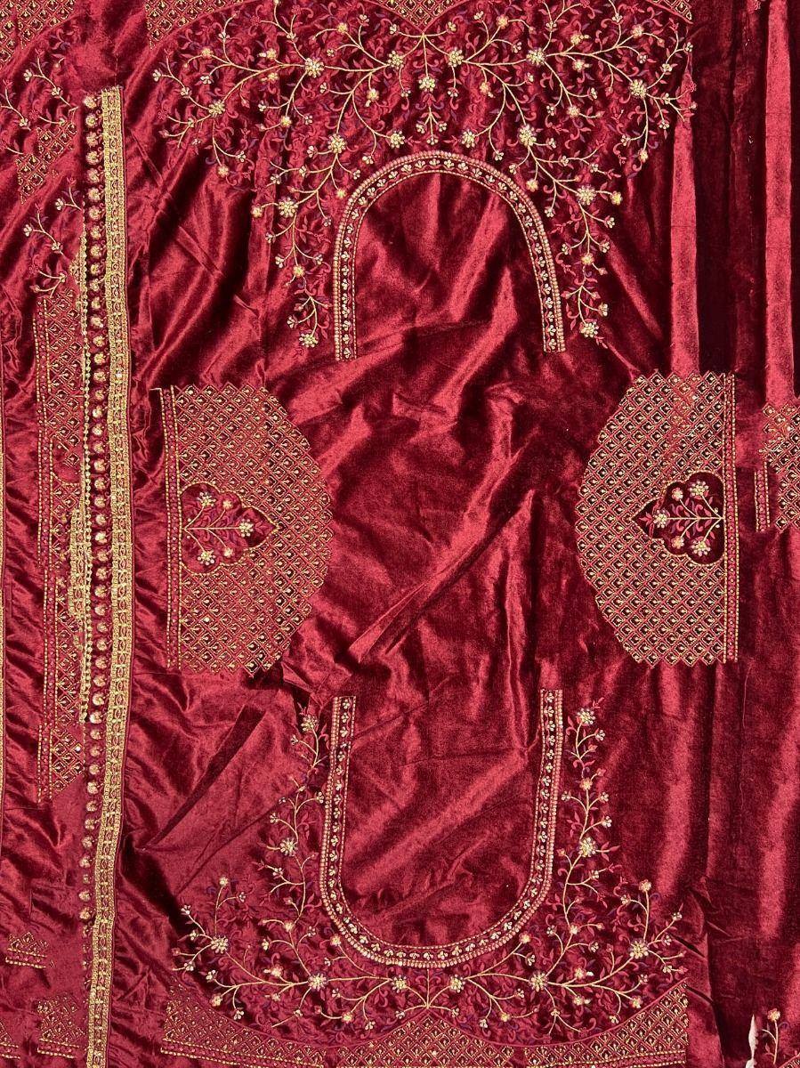 Rich maroon velvet salwar kameez with intricate gold embroidery and floral motifs, perfect for festive occasions.