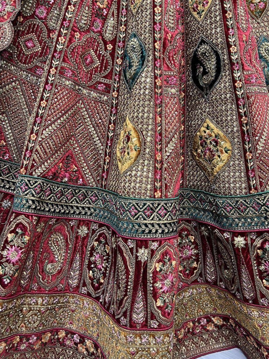 Richly embroidered maroon lehenga with gold paisley and floral motifs, perfect for Indian ethnic wear.