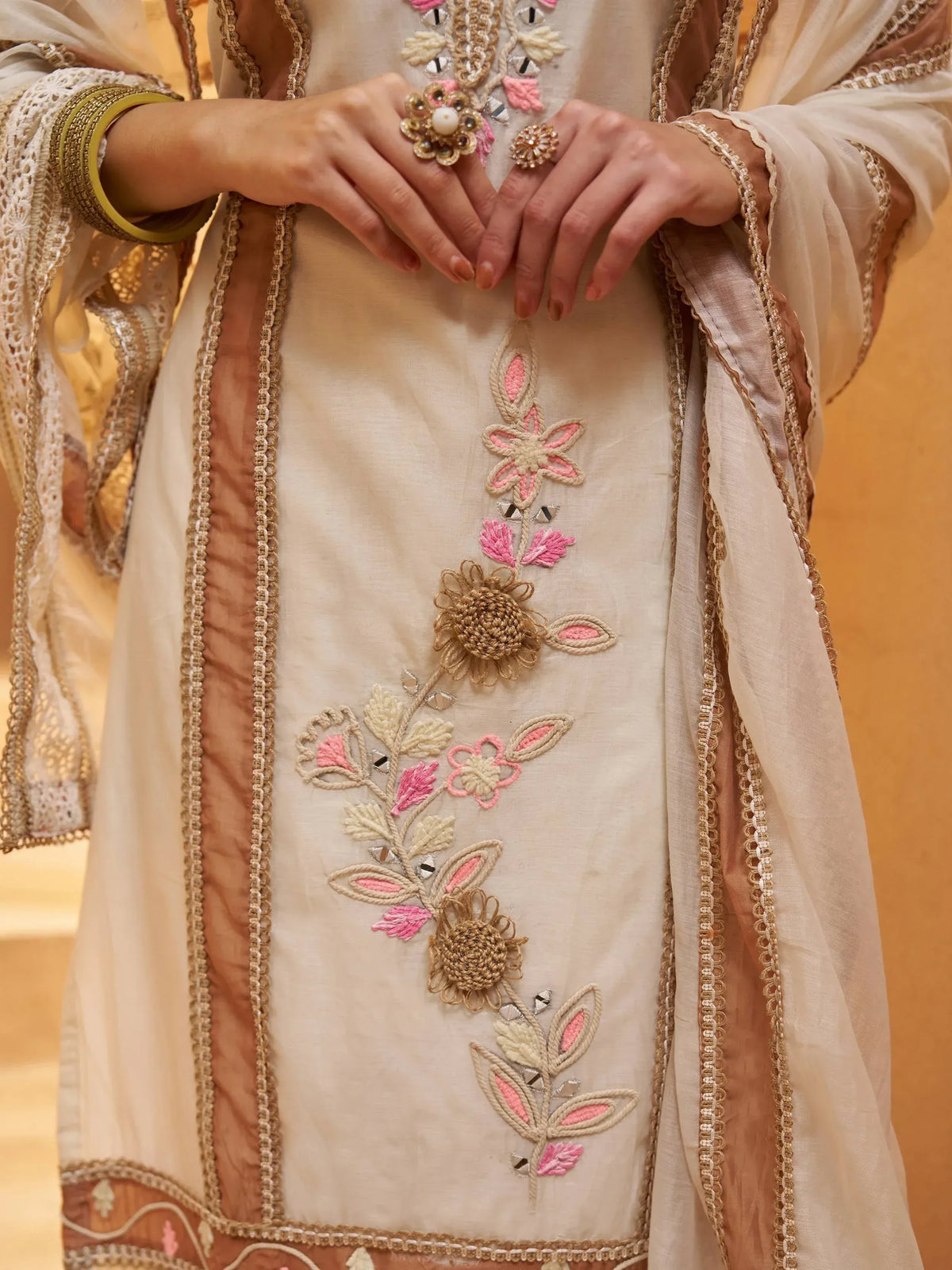 Elegant beige salwar kameez with pink floral embroidery and gold detailing, paired with matching dupatta.