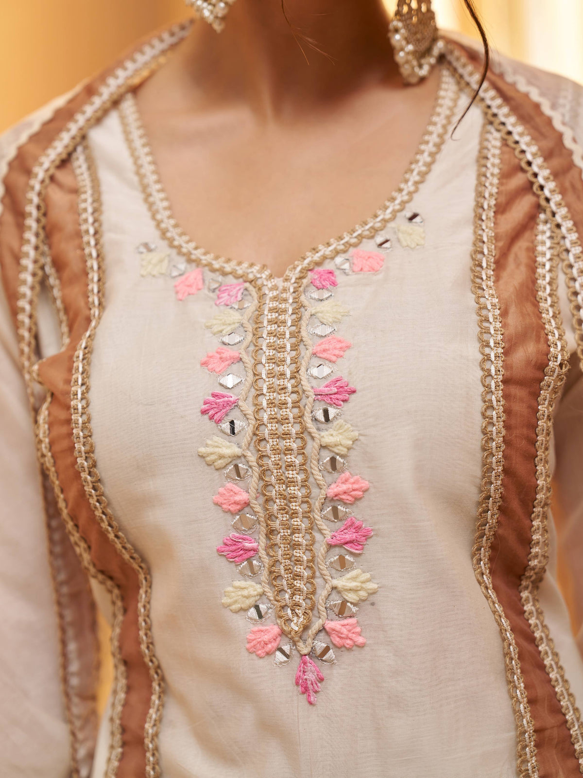 Beige ethnic kurti with pink floral embroidery, mirror work, and gold trim detailing