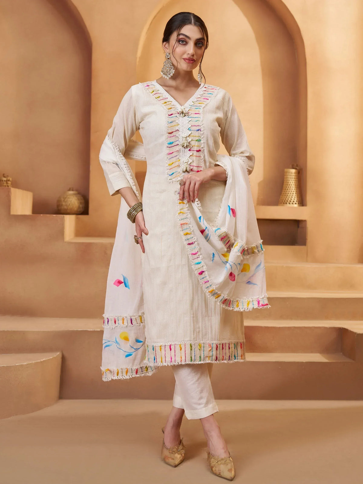 White embroidered salwar kameez with colorful threadwork, perfect for ethnic wear and festive occasions.