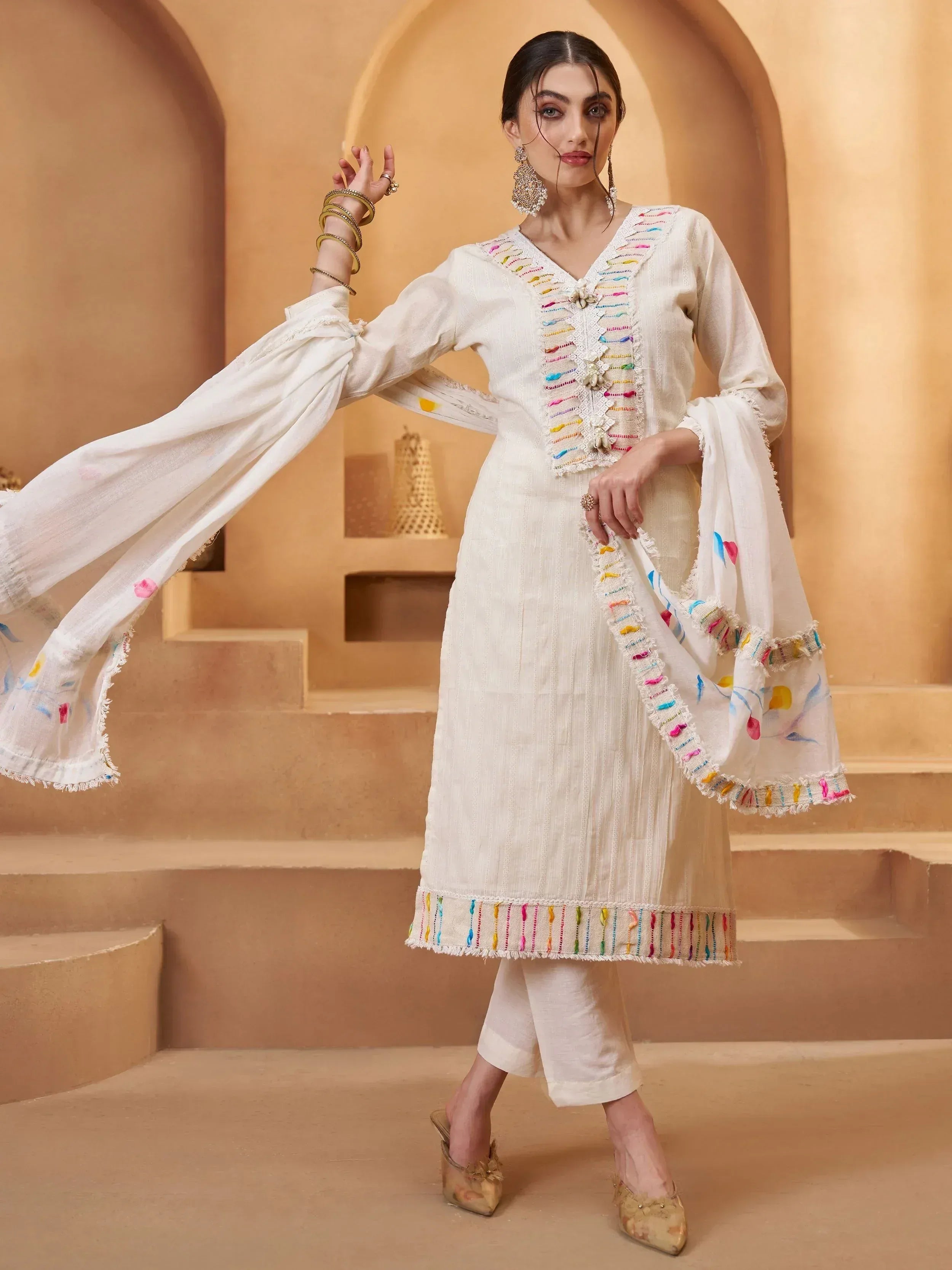 White ethnic salwar kameez with colorful thread embroidery and matching dupatta, ideal for festive occasions.