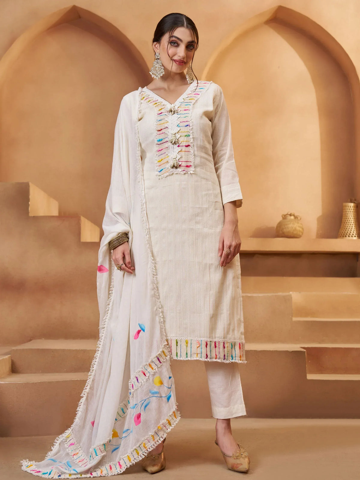 White embroidered salwar kameez with colorful threadwork, perfect for ethnic wear and festive occasions.