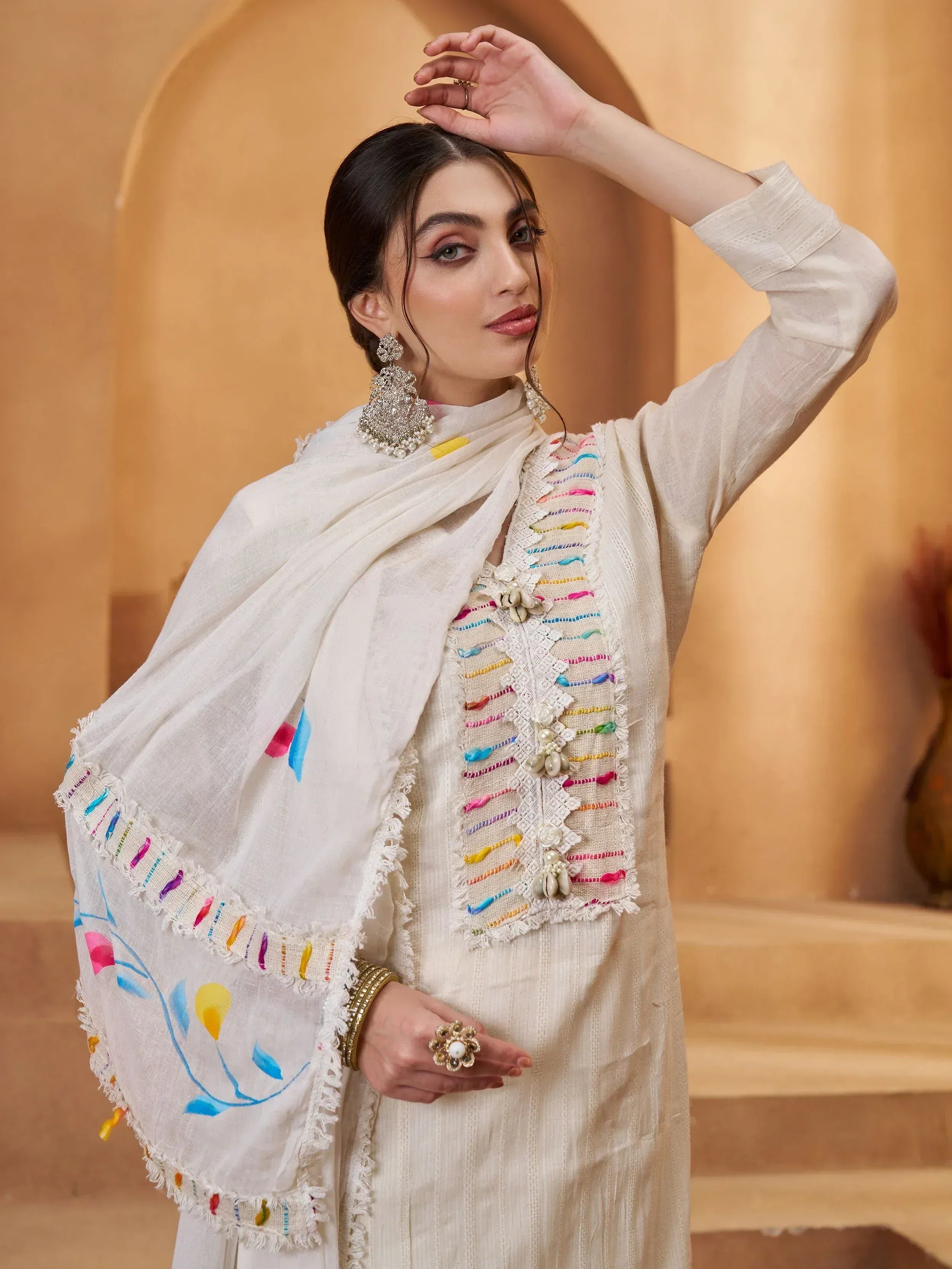 White ethnic kurta with colorful thread embroidery and matching dupatta, styled with statement earrings for festive occasions
