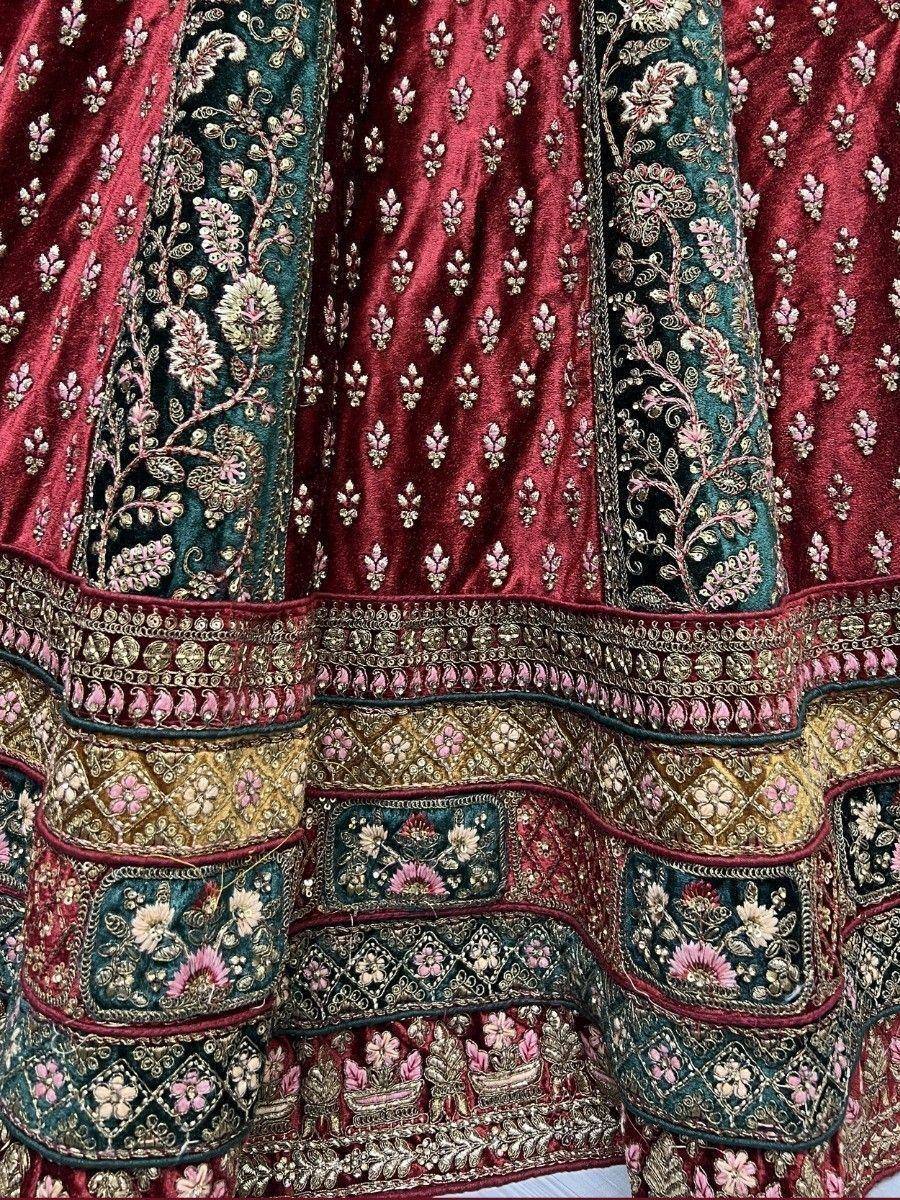 Luxury maroon and teal velvet lehenga with intricate floral embroidery and gold detailing, perfect for weddings.