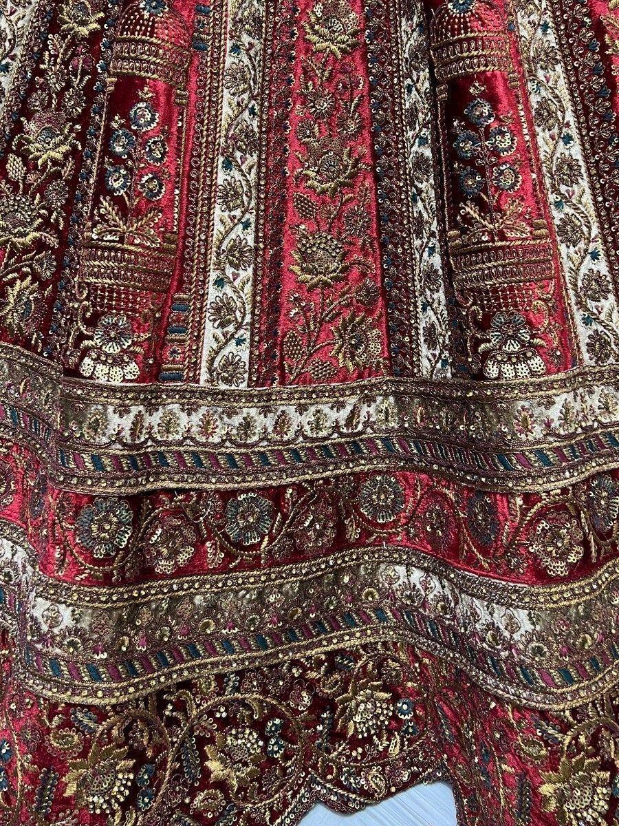 Richly embroidered red velvet lehenga with gold floral motifs and intricate border detailing