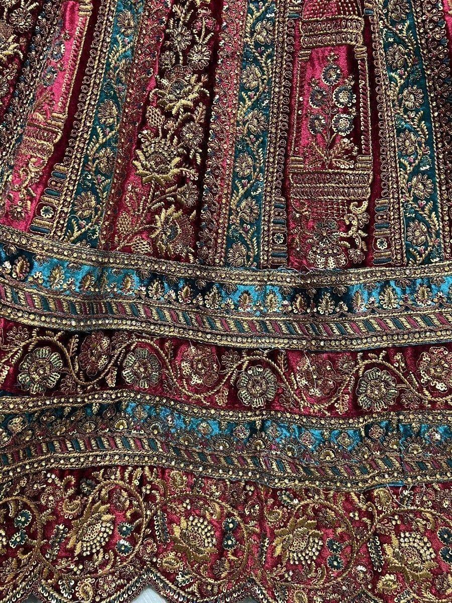Richly embroidered Indian lehenga with gold floral motifs on maroon and teal velvet fabric