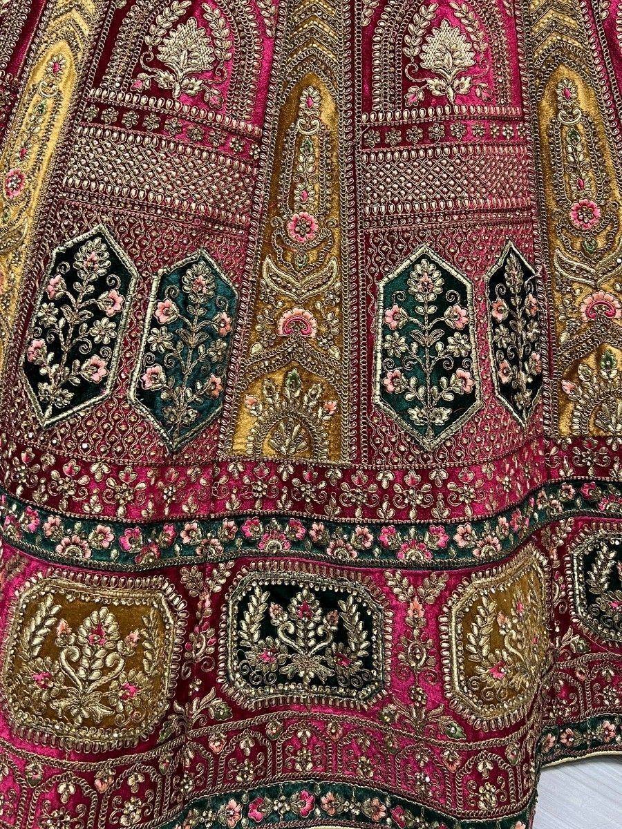 Richly embroidered Indian lehenga with gold, pink, and green floral motifs and intricate zari work.