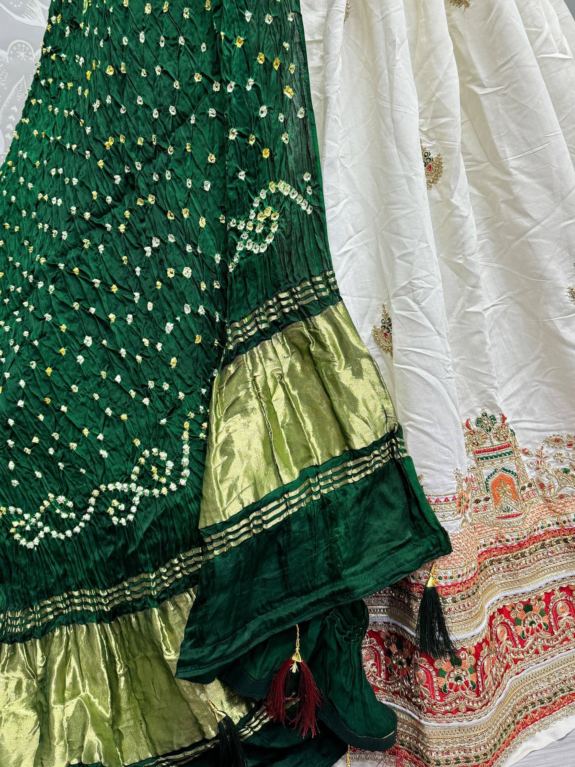 Emerald green embroidered lehenga with gold detailing and tassels, paired with white ethnic wear