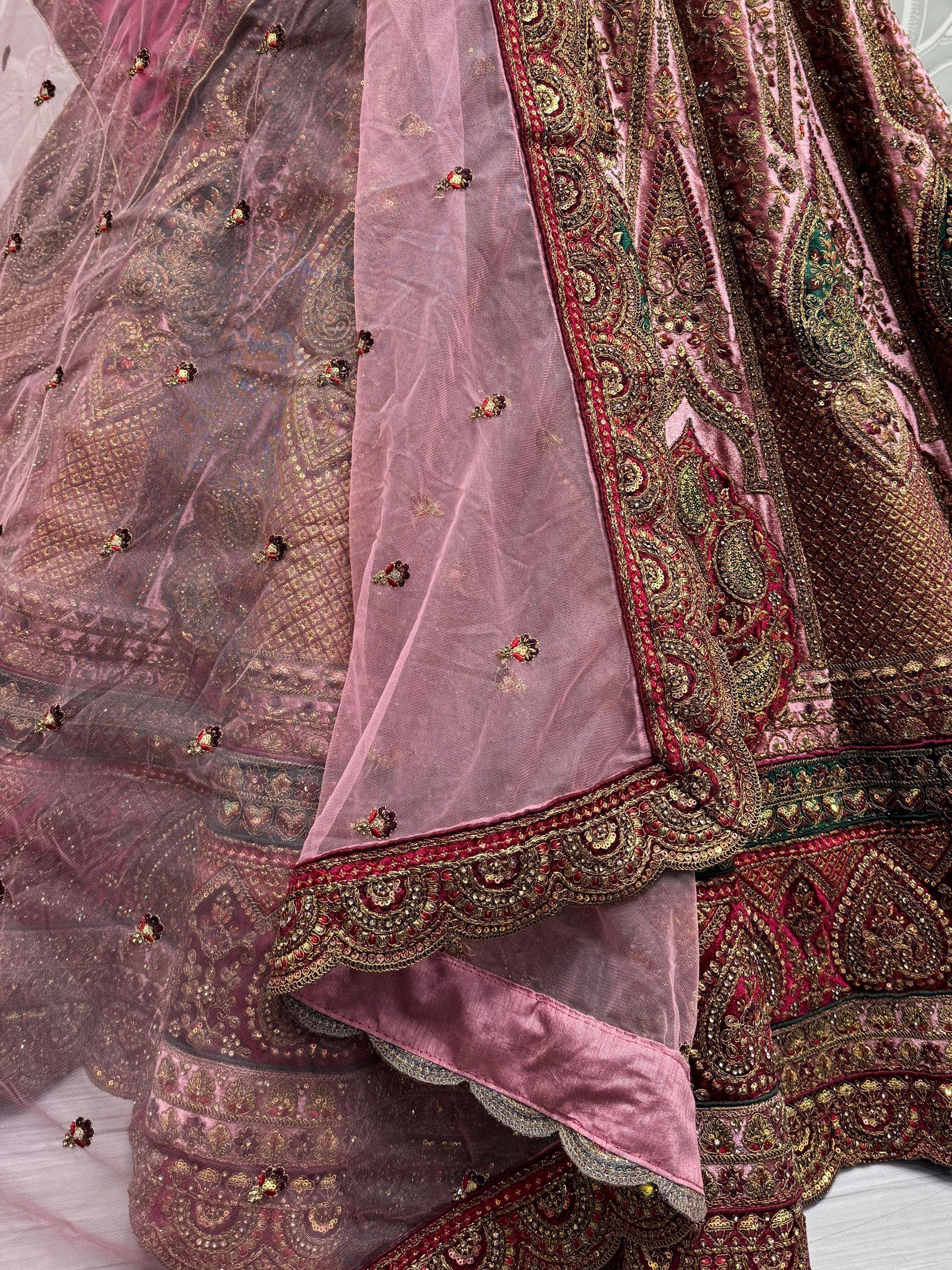 Luxury pink velvet lehenga choli with heavy gold embroidery and net dupatta, perfect for Indian weddings.