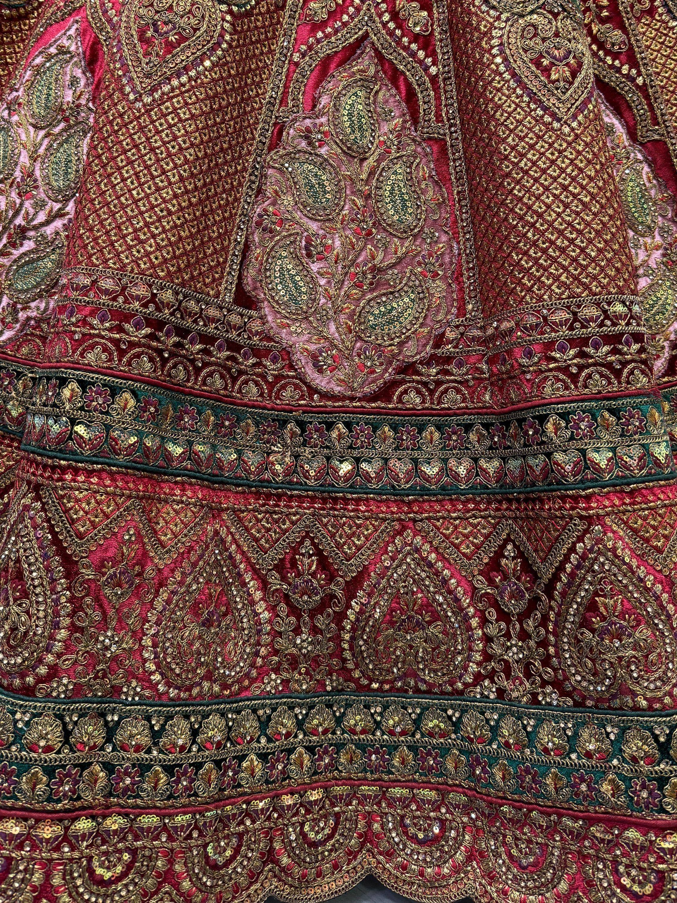 Richly embroidered maroon Indian ethnic wear with gold paisley and floral motifs, perfect for festive occasions.