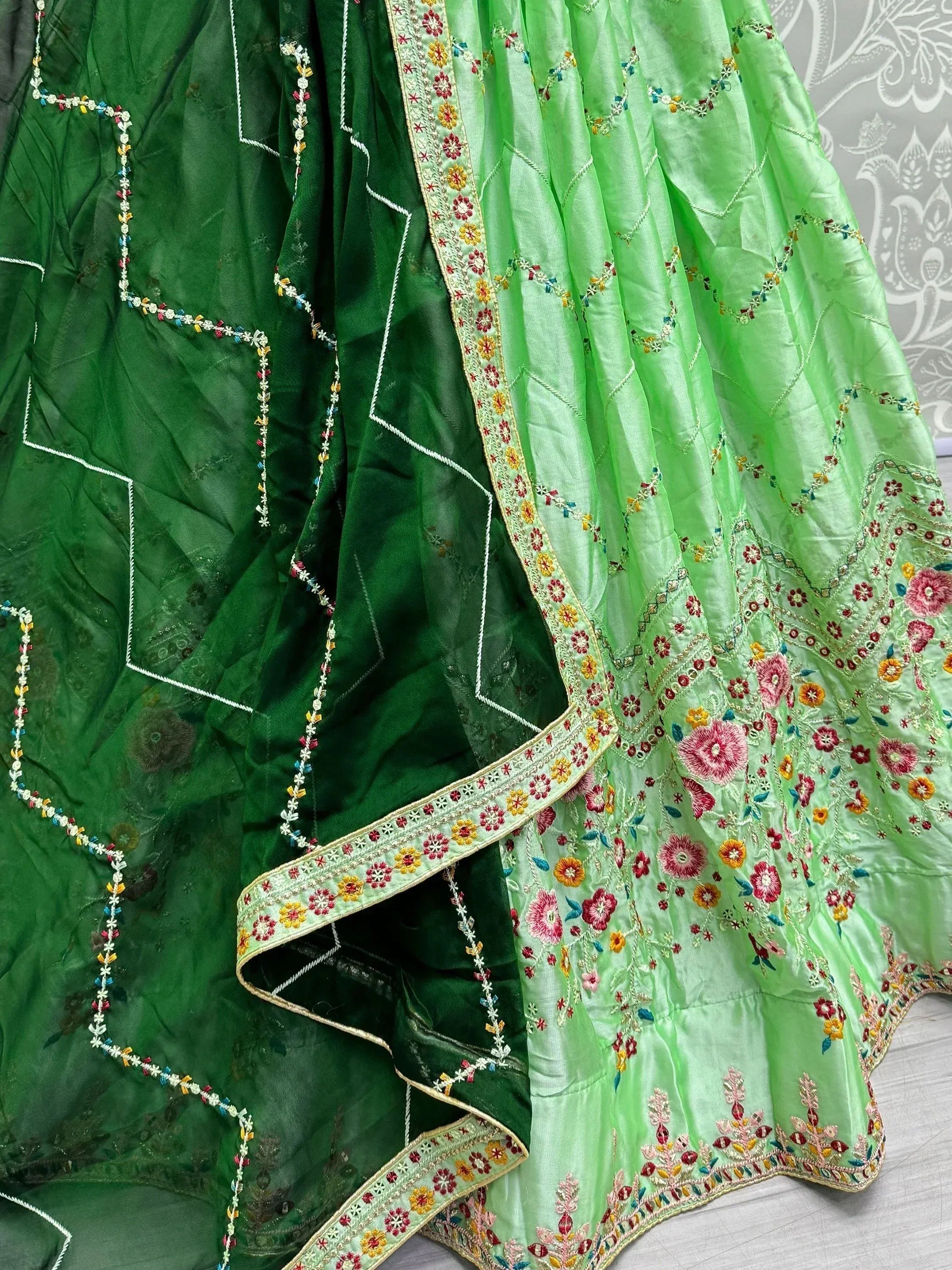 Green embroidered lehenga choli with floral motifs and colorful threadwork, ideal for Indian ethnic wear.