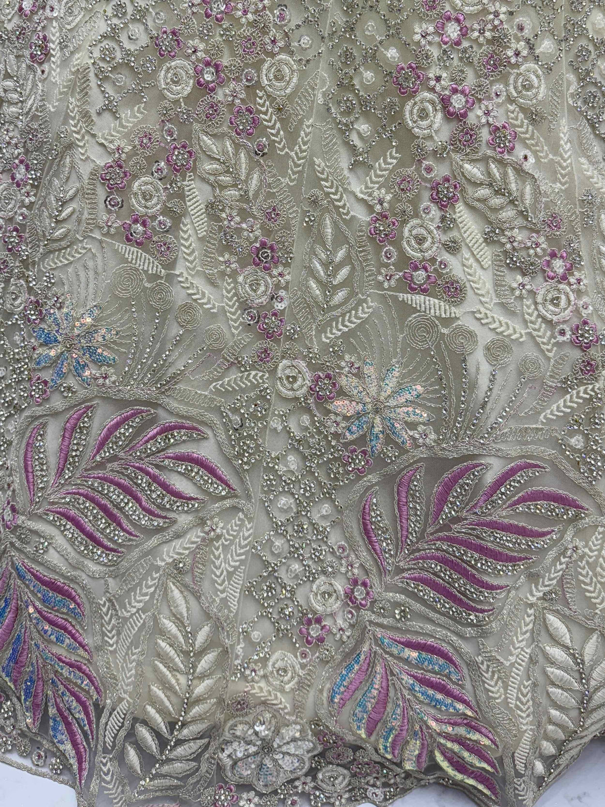 Luxury ethnic wear fabric with intricate floral embroidery, sequins, and beadwork in purple and silver tones.