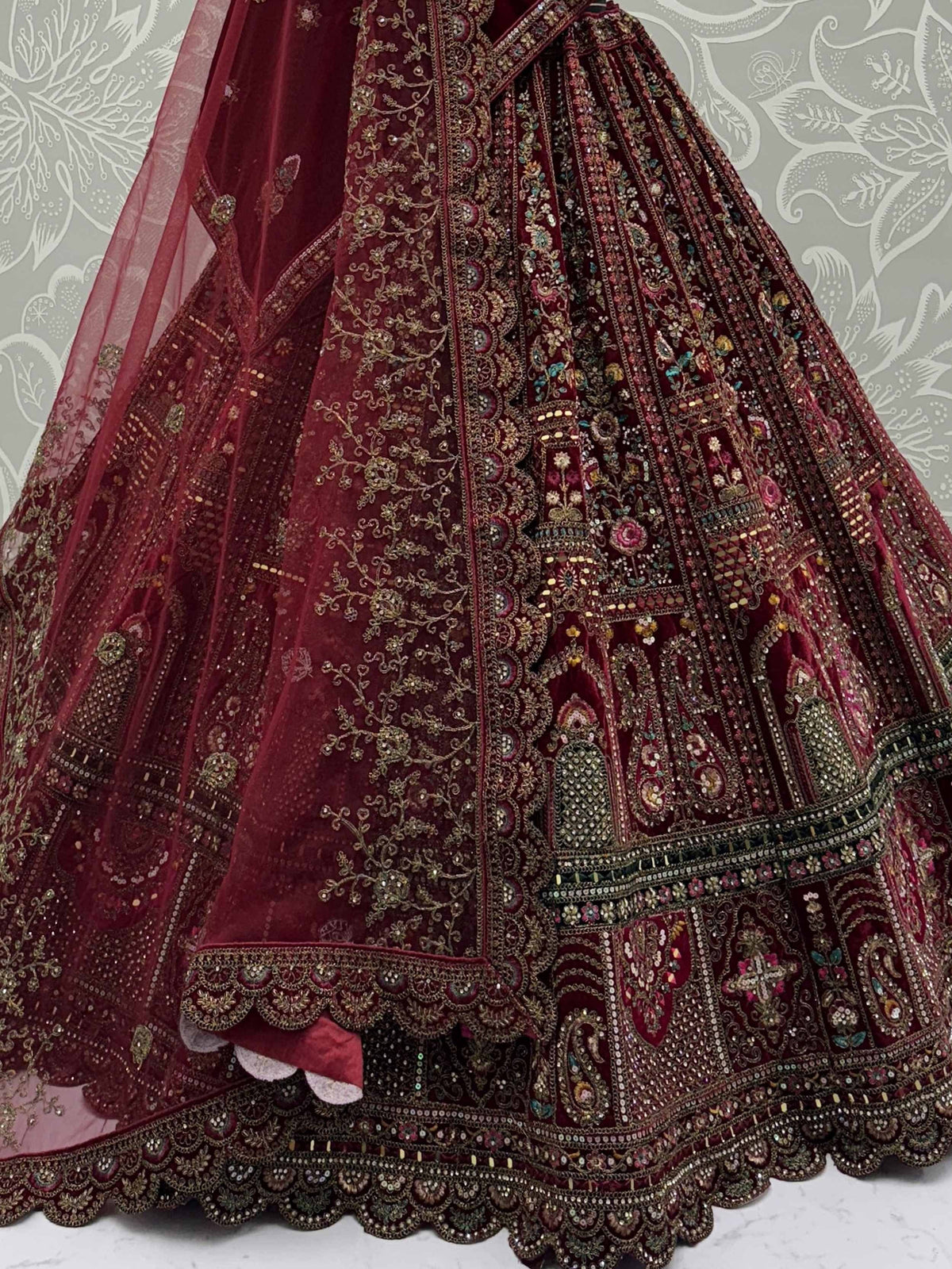 Maroon velvet lehenga choli with intricate gold embroidery and mirror work, perfect for weddings and festivals.