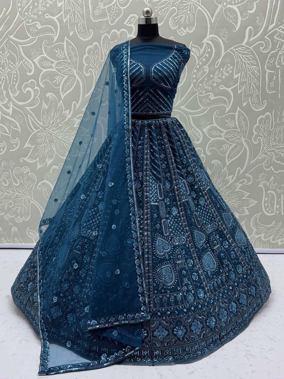 Teal blue designer lehenga choli with heavy embroidery and sequins, perfect for Indian weddings and festive occasions.