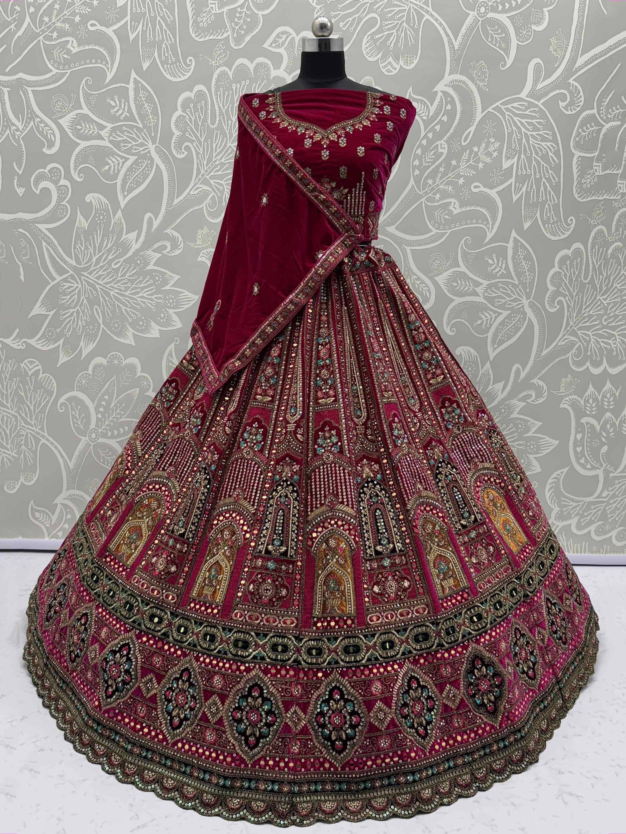 Burgundy velvet designer lehenga choli with heavy embroidery and mirror work, perfect for Indian weddings and festive occasions.