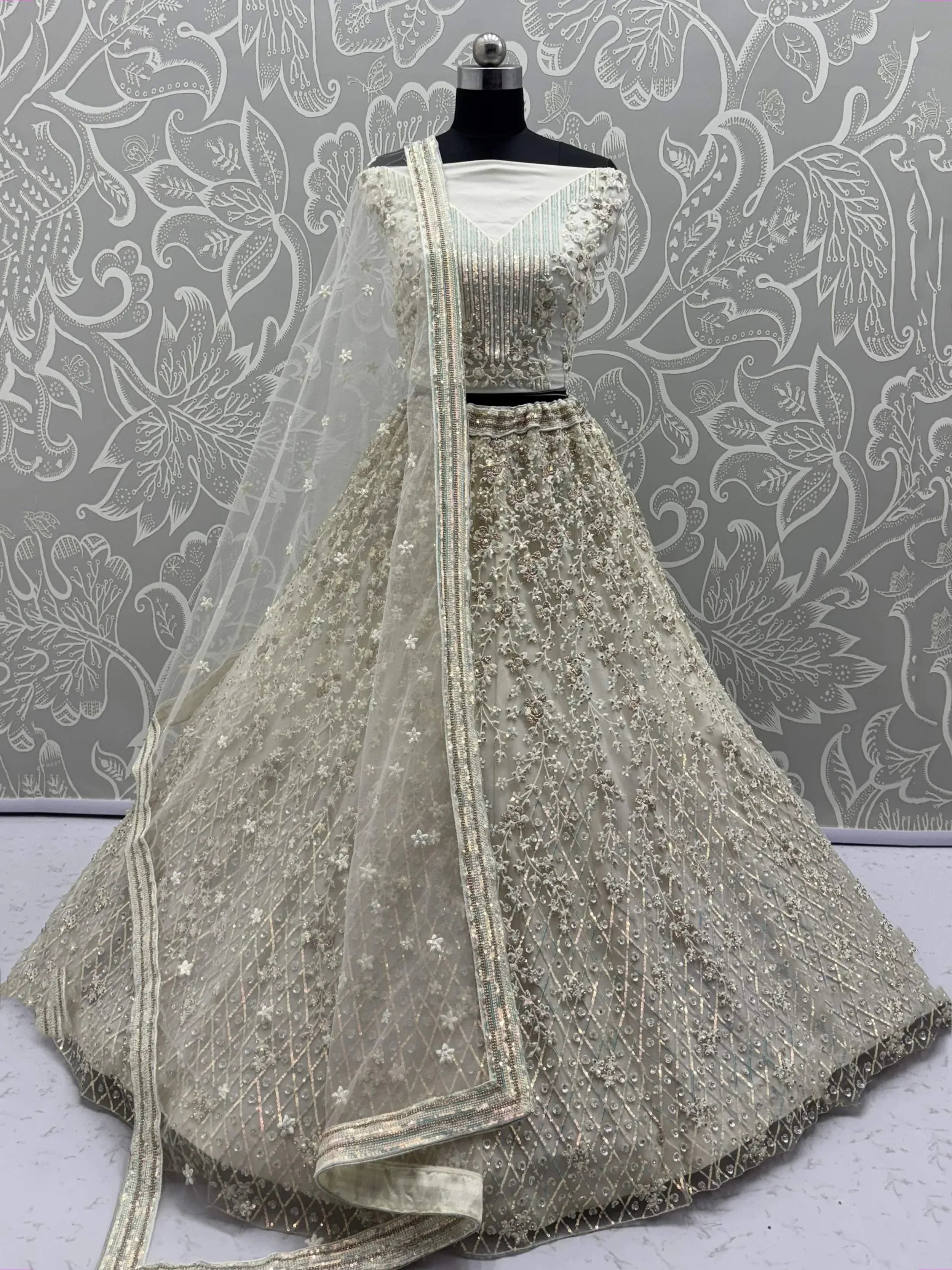Elegant off-white designer lehenga choli with intricate embroidery and sheer dupatta for Indian ethnic wear.