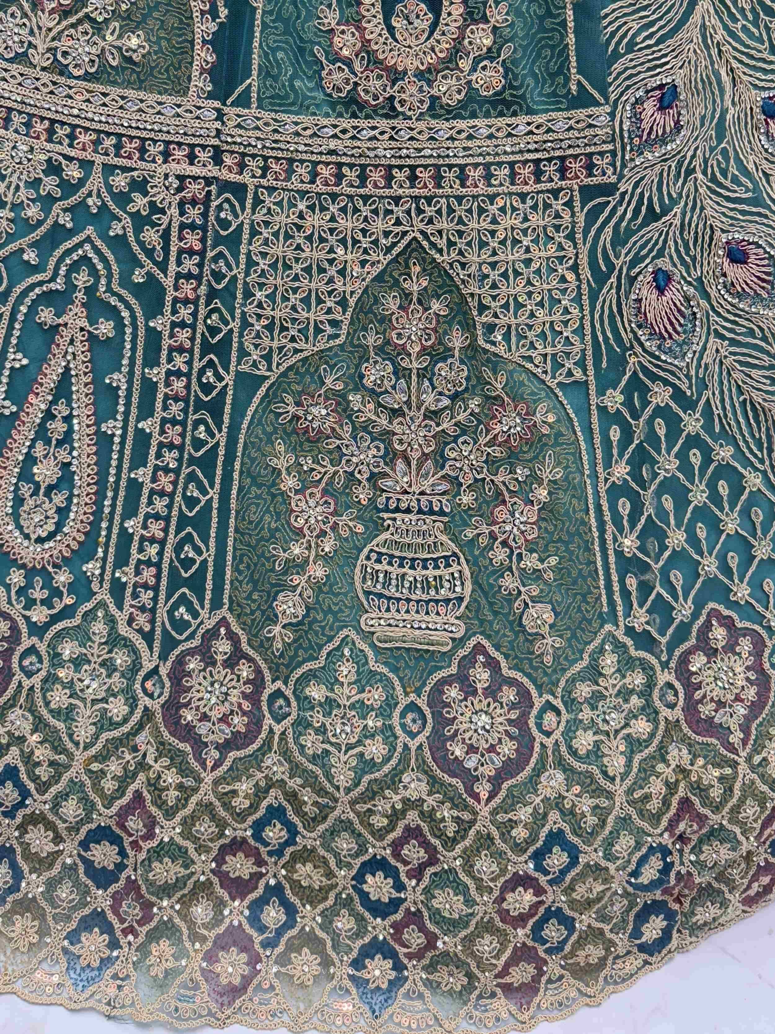 Teal designer lehenga with intricate gold embroidery, floral motifs, and peacock detailing for Indian ethnic wear.