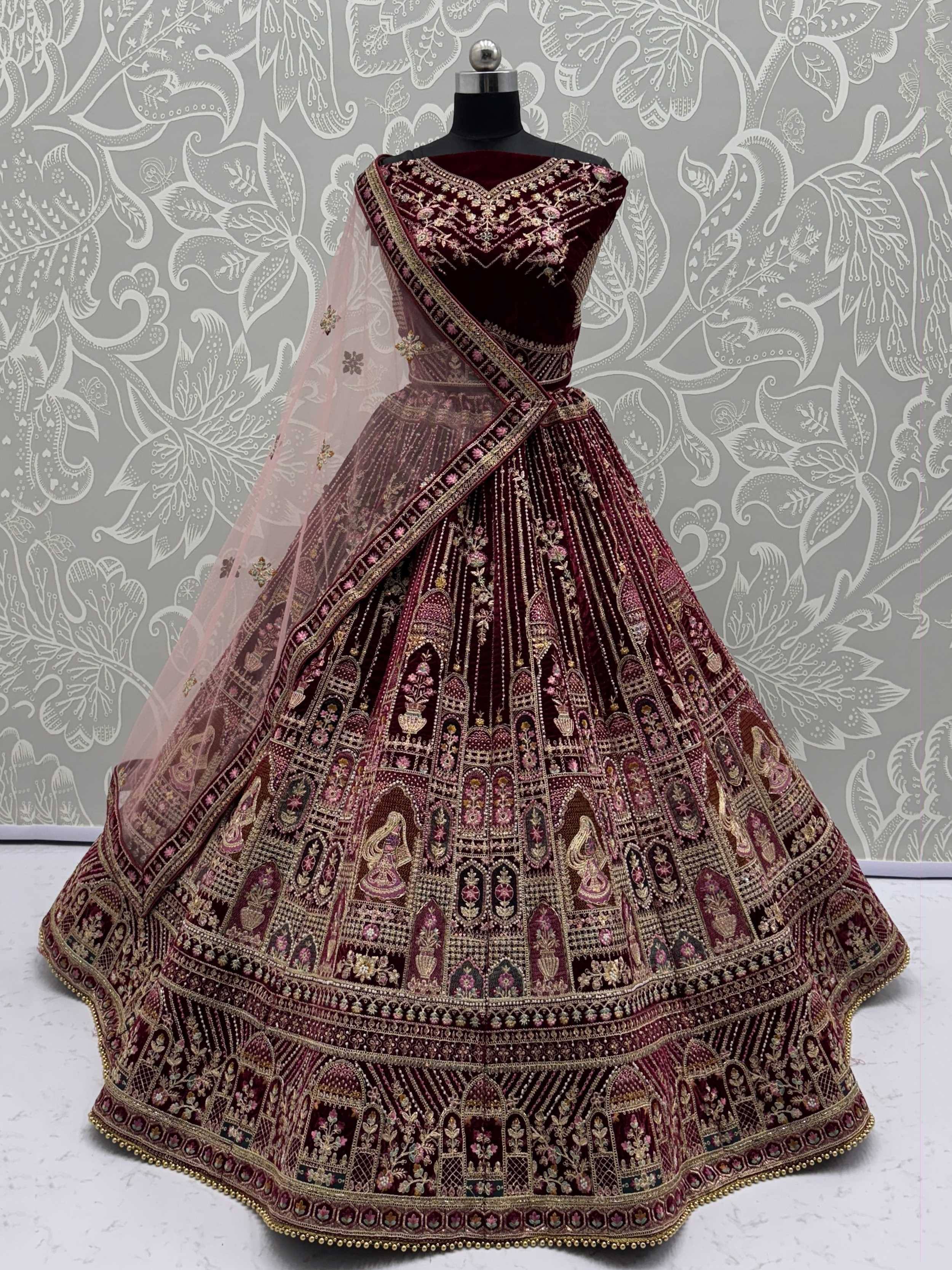 Maroon velvet designer lehenga choli with heavy gold embroidery and sheer dupatta, perfect for Indian weddings.
