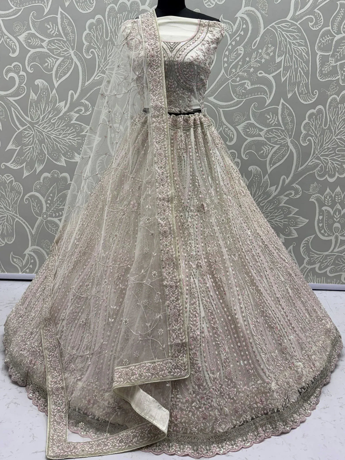 Elegant ivory lehenga choli with intricate pink embroidery and sequin work, perfect for weddings and festive occasions.
