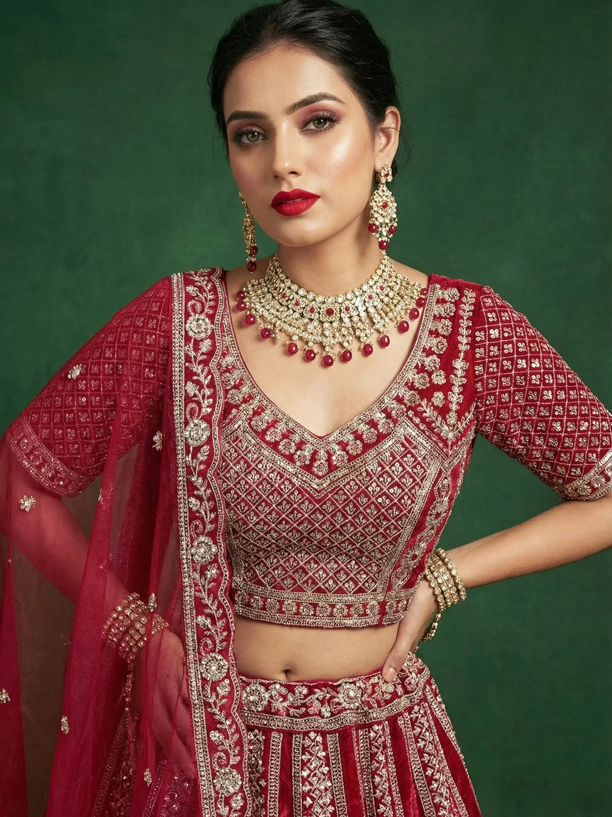 Elegant red embroidered lehenga choli with gold detailing and matching jewelry