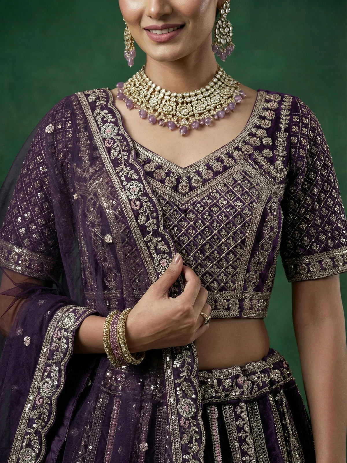 Purple embroidered lehenga choli with gold detailing and matching jewelry