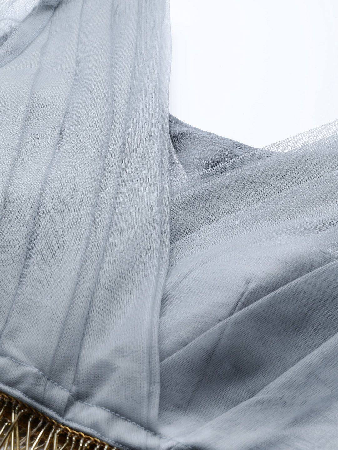 Grey sheer ethnic gown with pleated detailing and gold trim, perfect for Indian occasions.