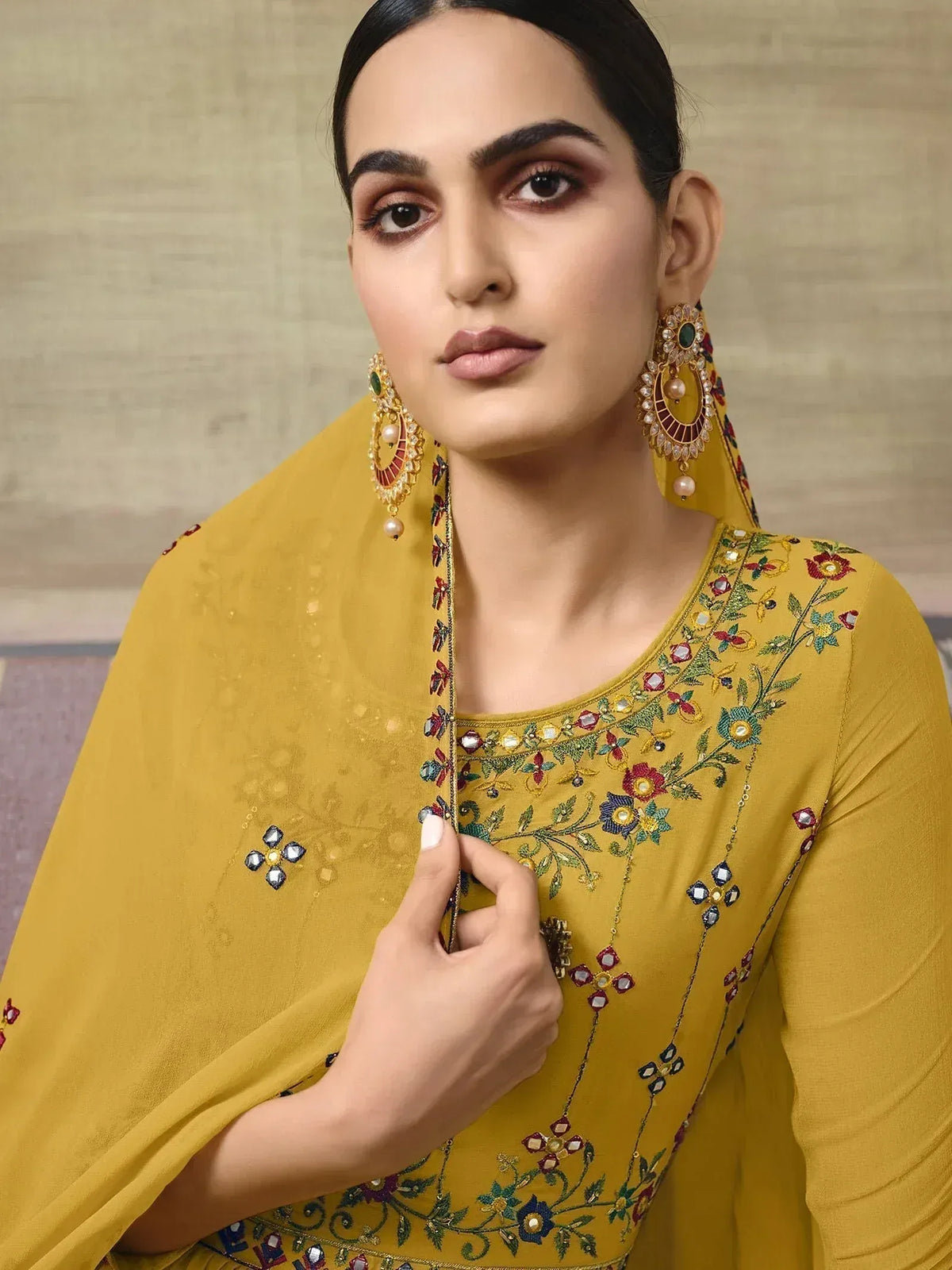 Yellow embroidered ethnic salwar kameez with floral detailing and matching dupatta, styled with statement earrings