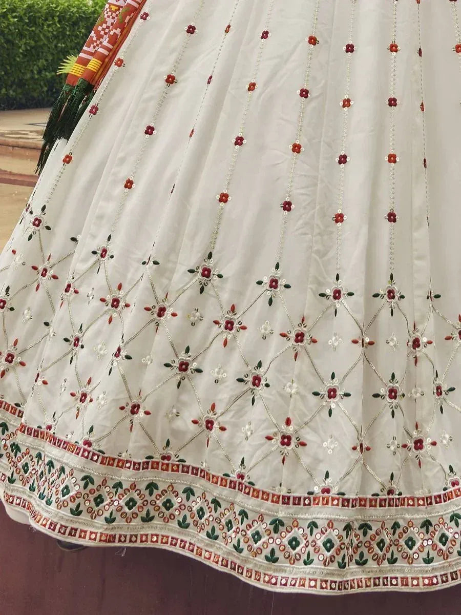 White lehenga with red and green floral embroidery, diamond patterns, and detailed border work for ethnic wear.