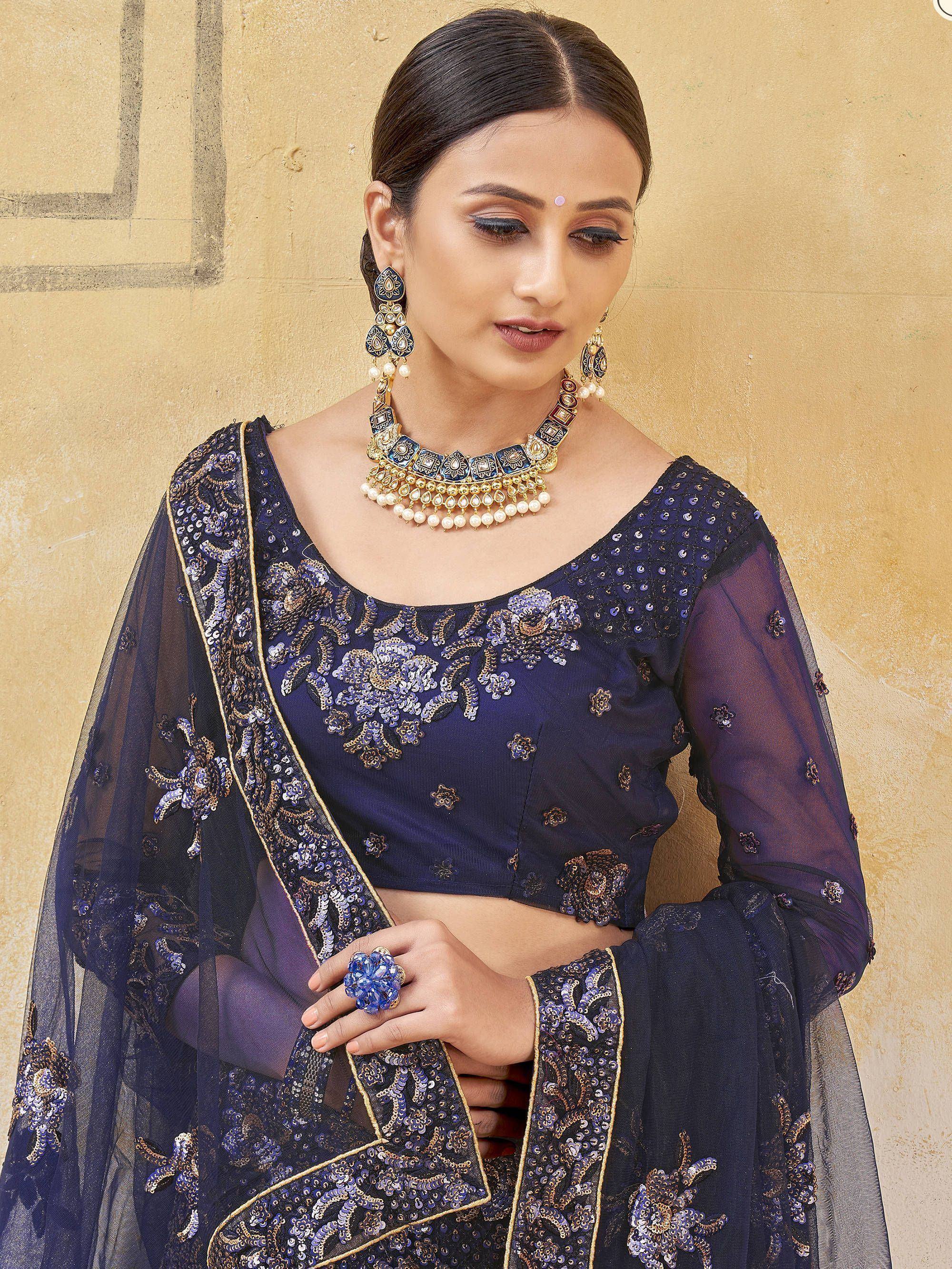 Navy blue embroidered lehenga choli with sheer sleeves and gold detailing, paired with traditional jewelry.